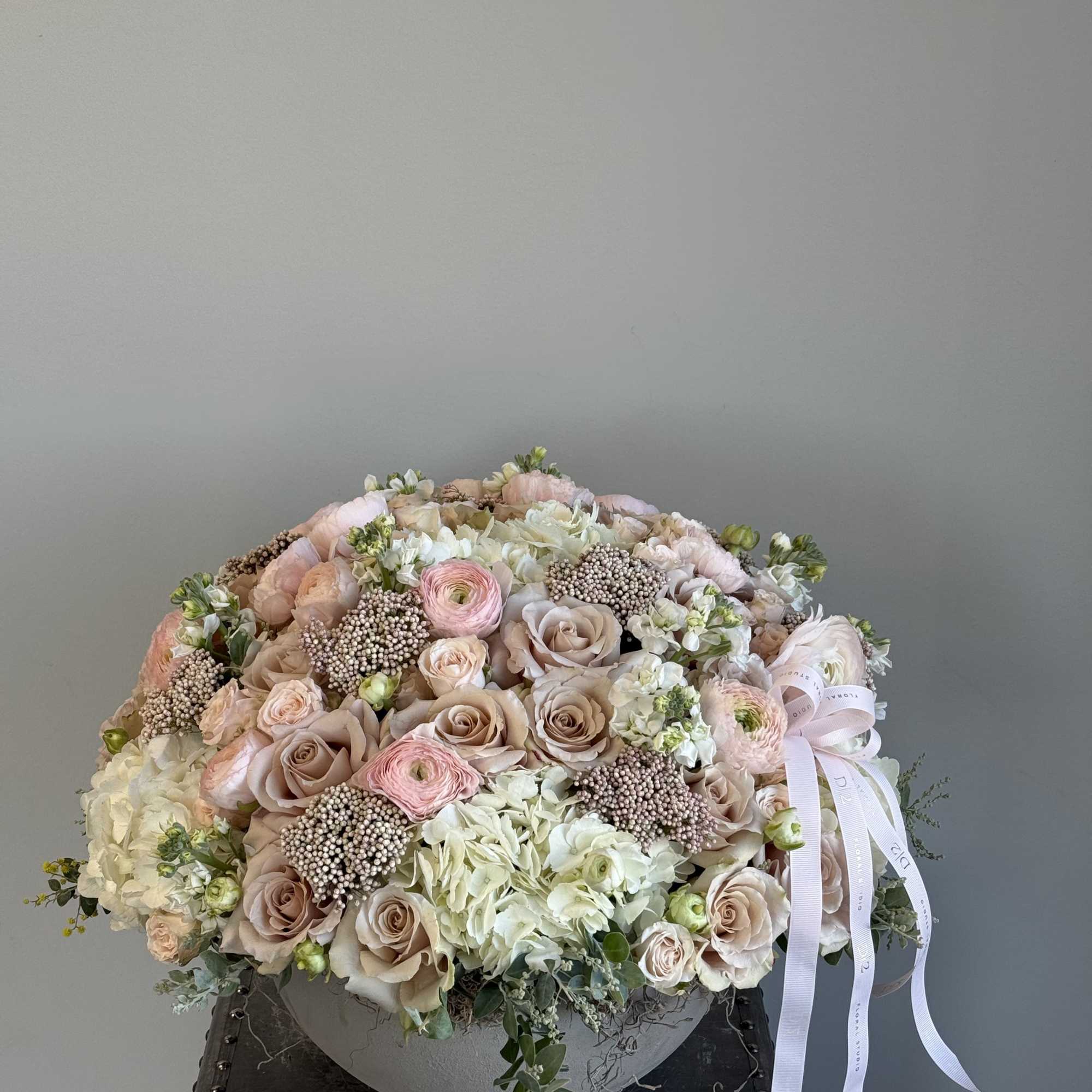 Large pastel bouquet of roses, ranunculus, and hydrangeas with a ribbon