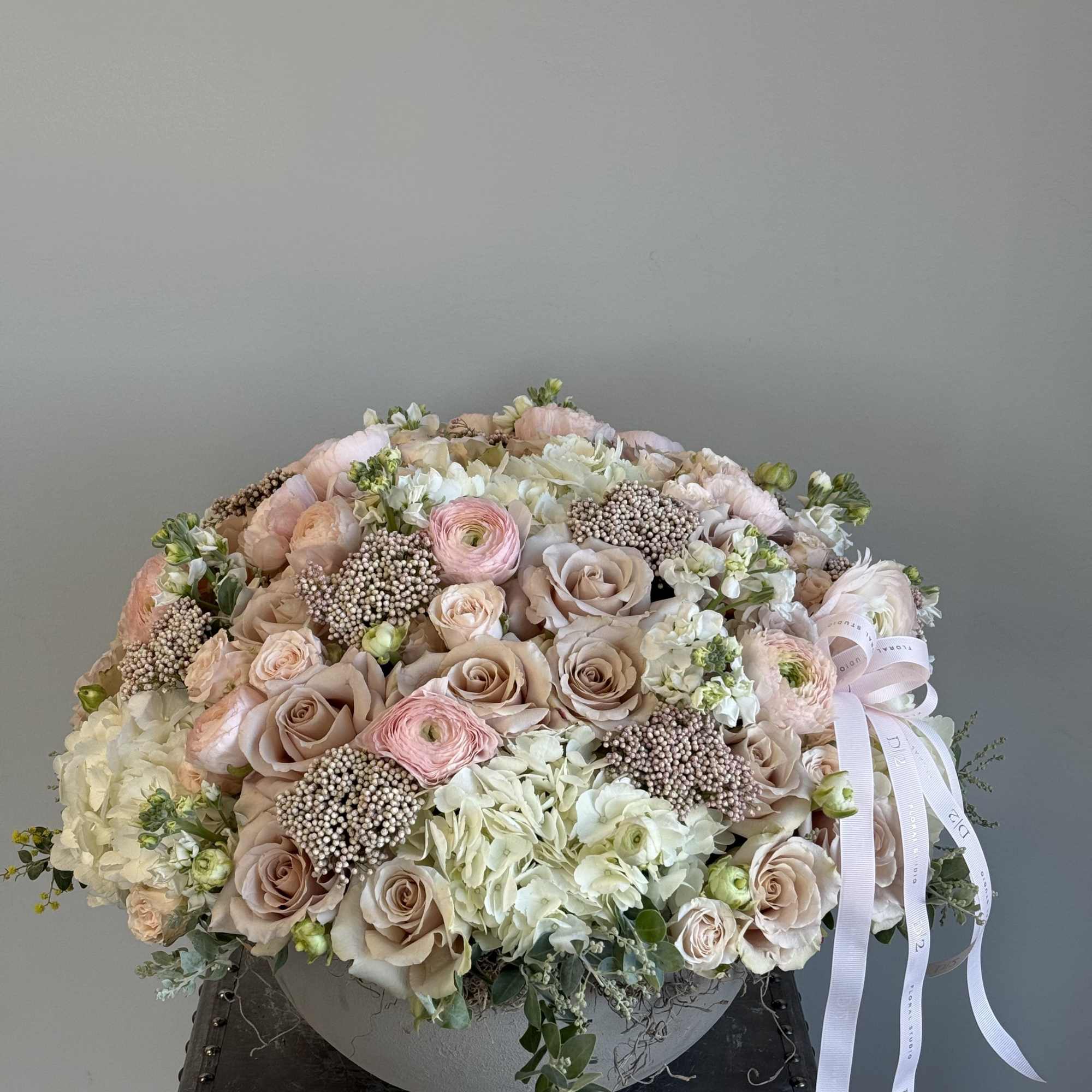 Blush and white rose bouquet in a low round container with ribbon