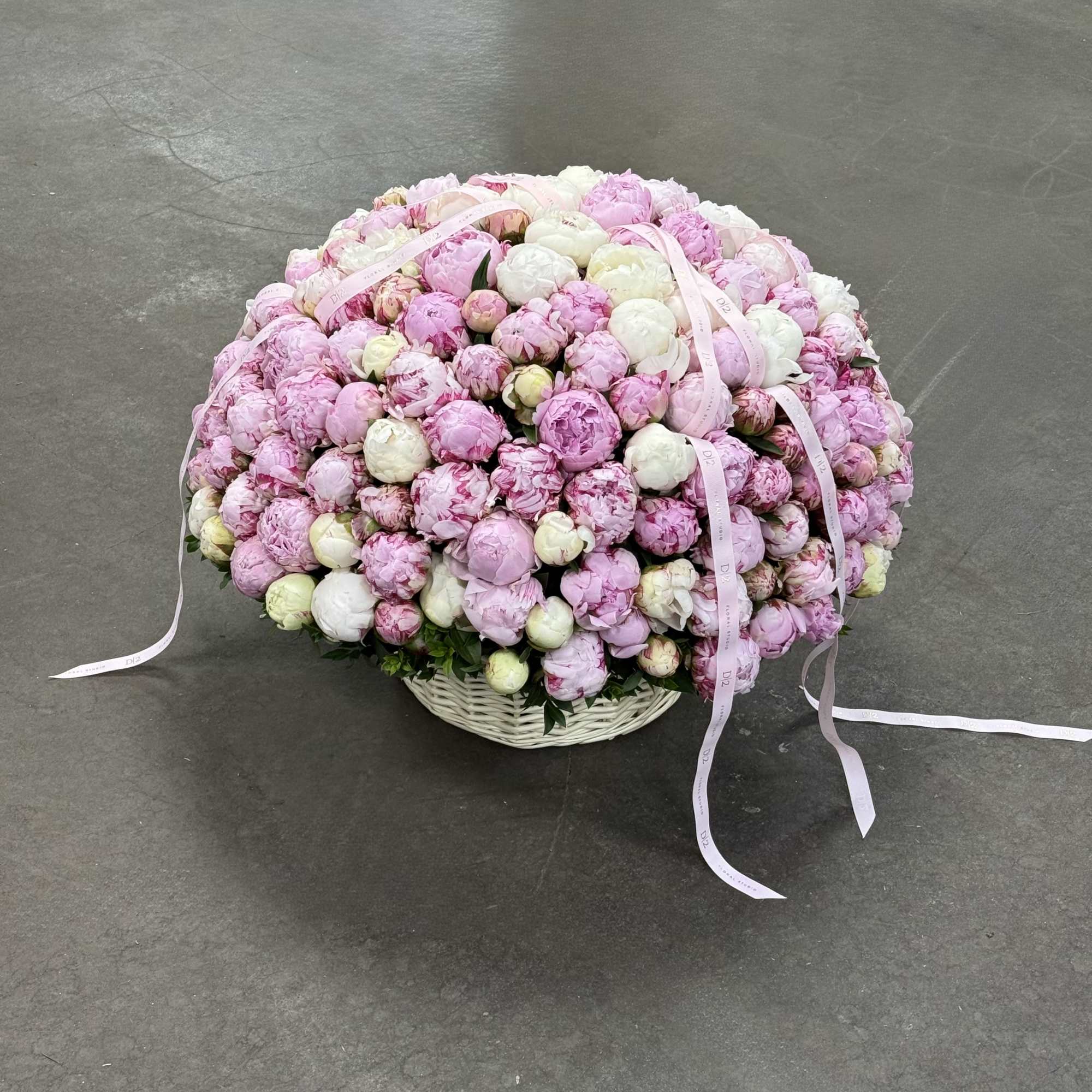 Large basket of pink and white peonies with ribbon streamers