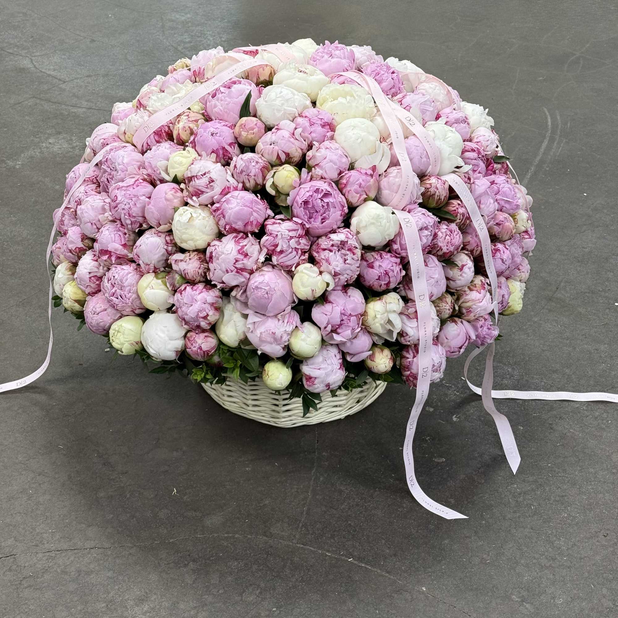 Large basket arrangement of pink and white peonies with ribbon streamers