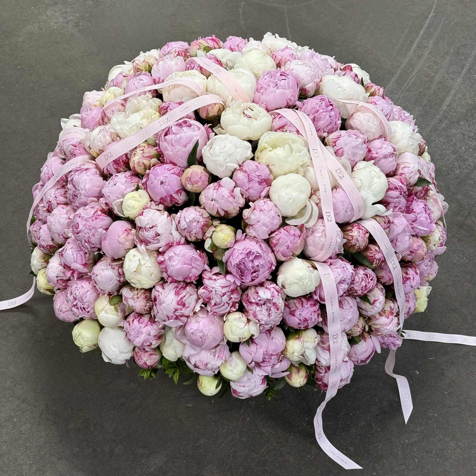 Large mound of pink and white peonies with pale pink ribbons