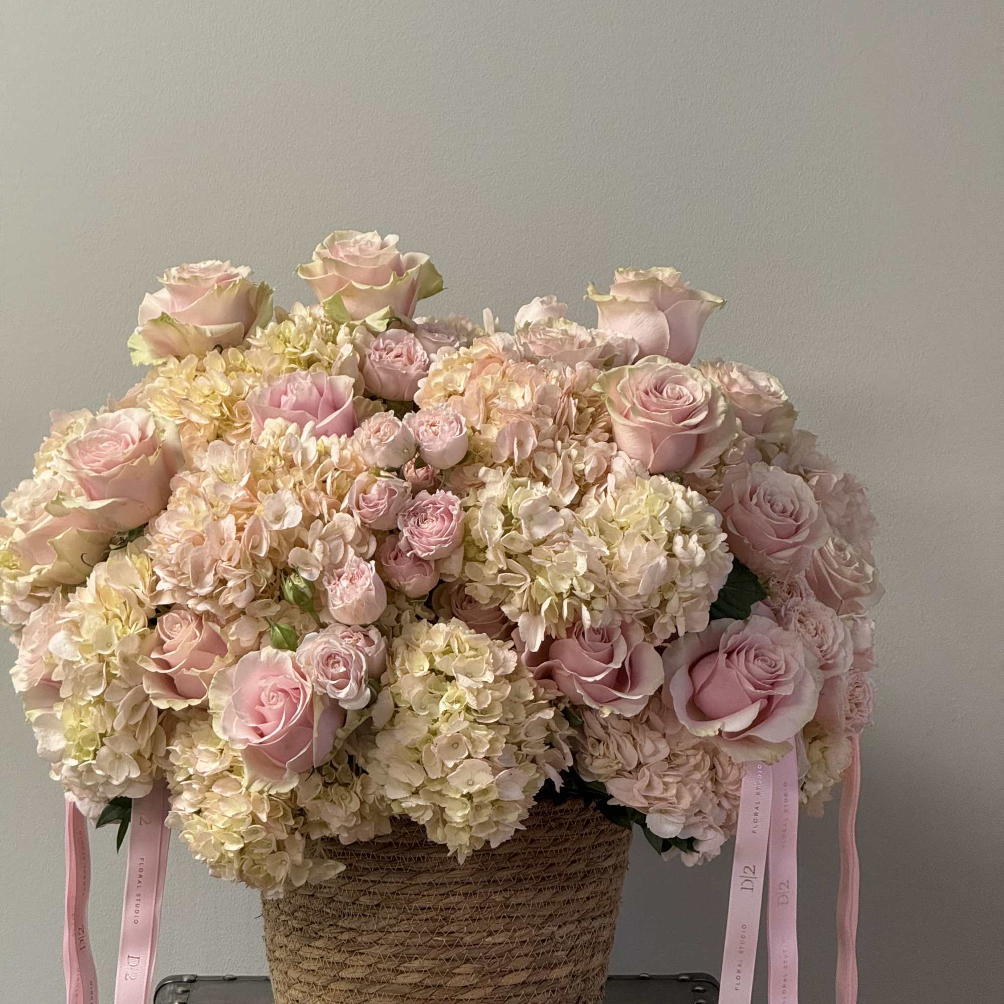 Large pink rose and hydrangea arrangement in a woven basket