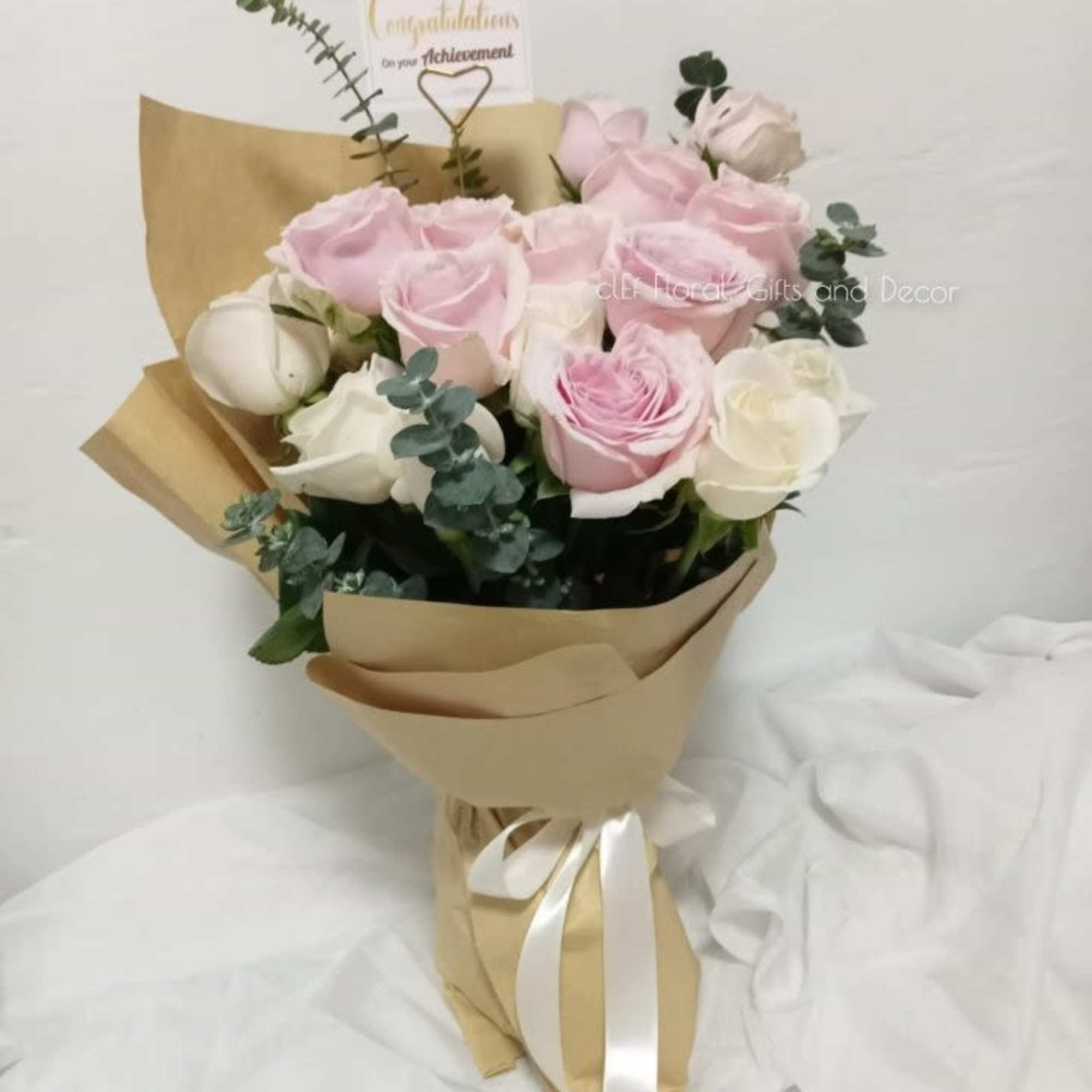 Pink and white rose bouquet wrapped in kraft paper with a ribbon