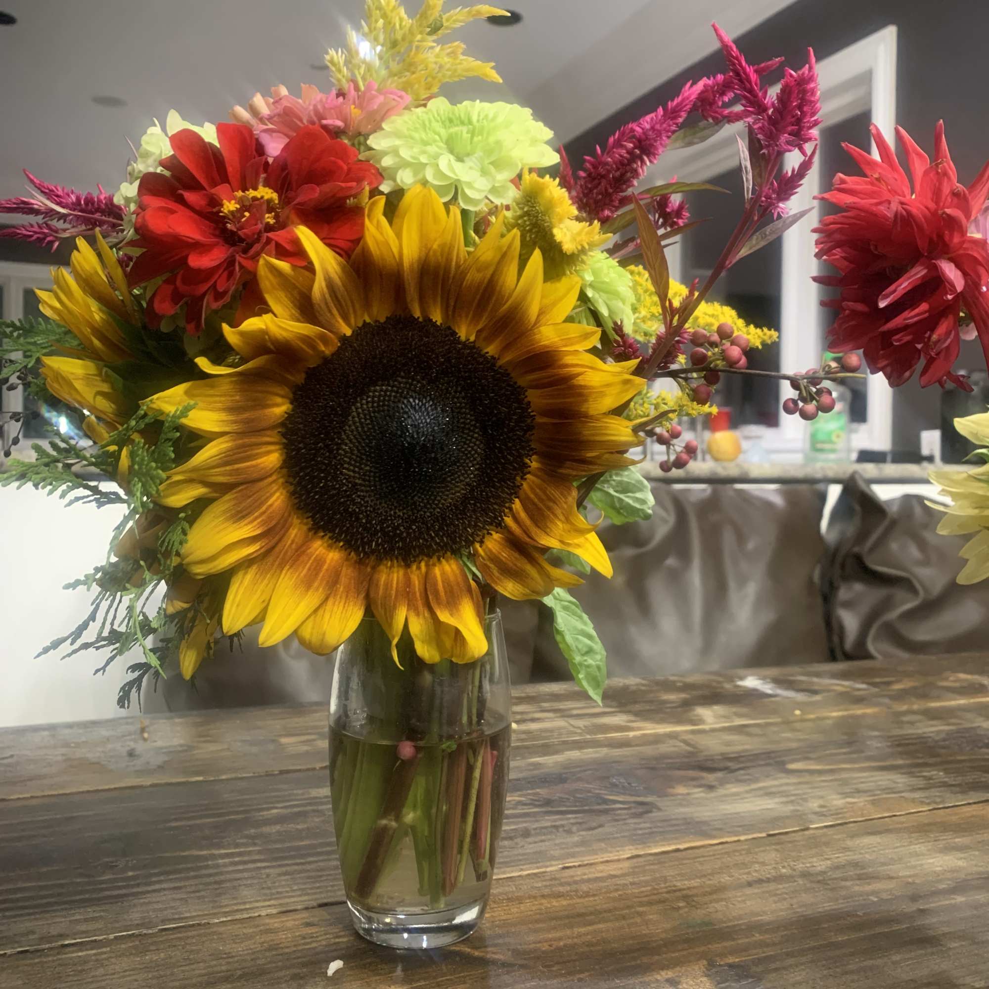Mixed bouquet with a large sunflower in a glass vase