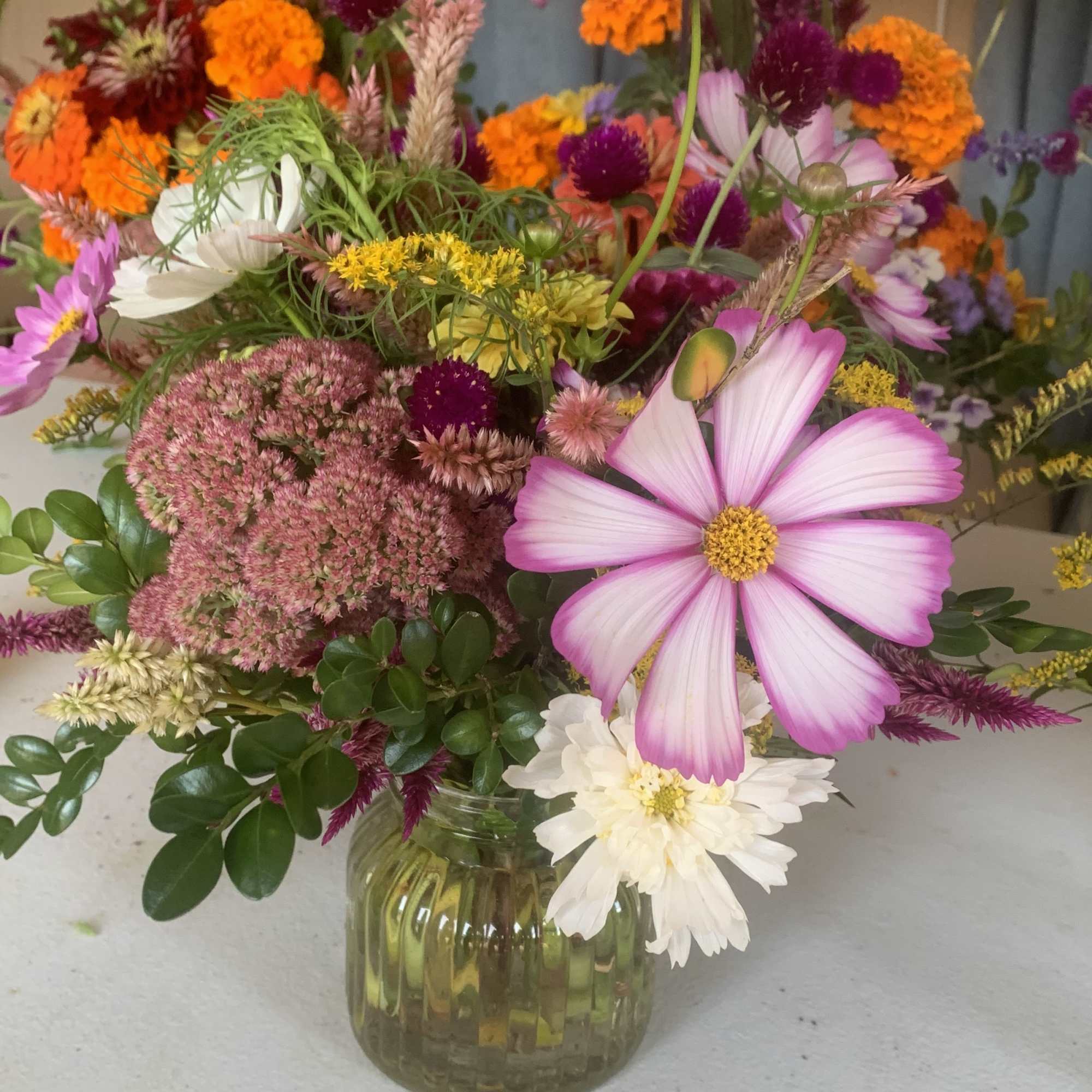 Mixed bouquet of pink, orange, white, and purple flowers in a glass vase