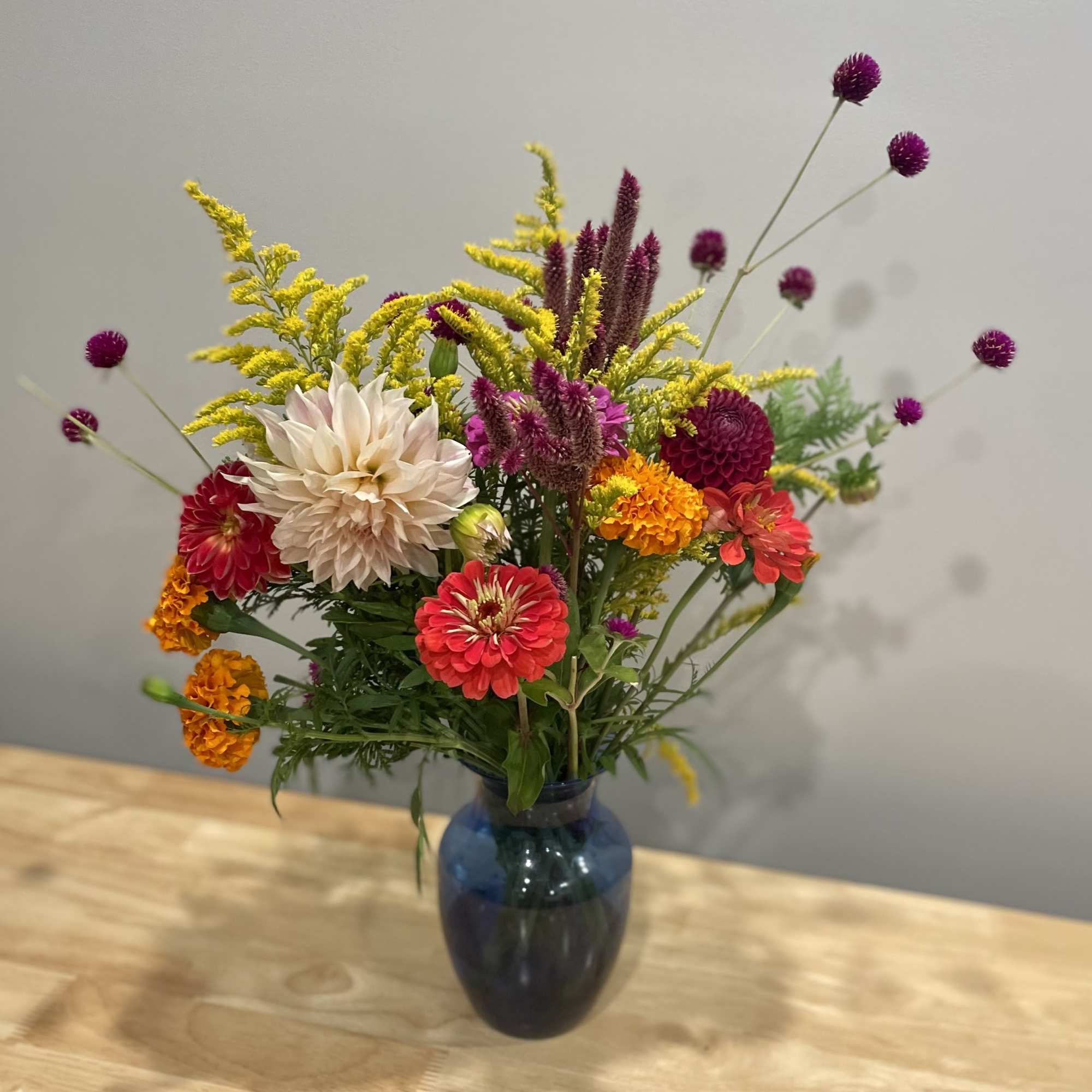 Mixed bouquet of colorful flowers in a blue glass vase