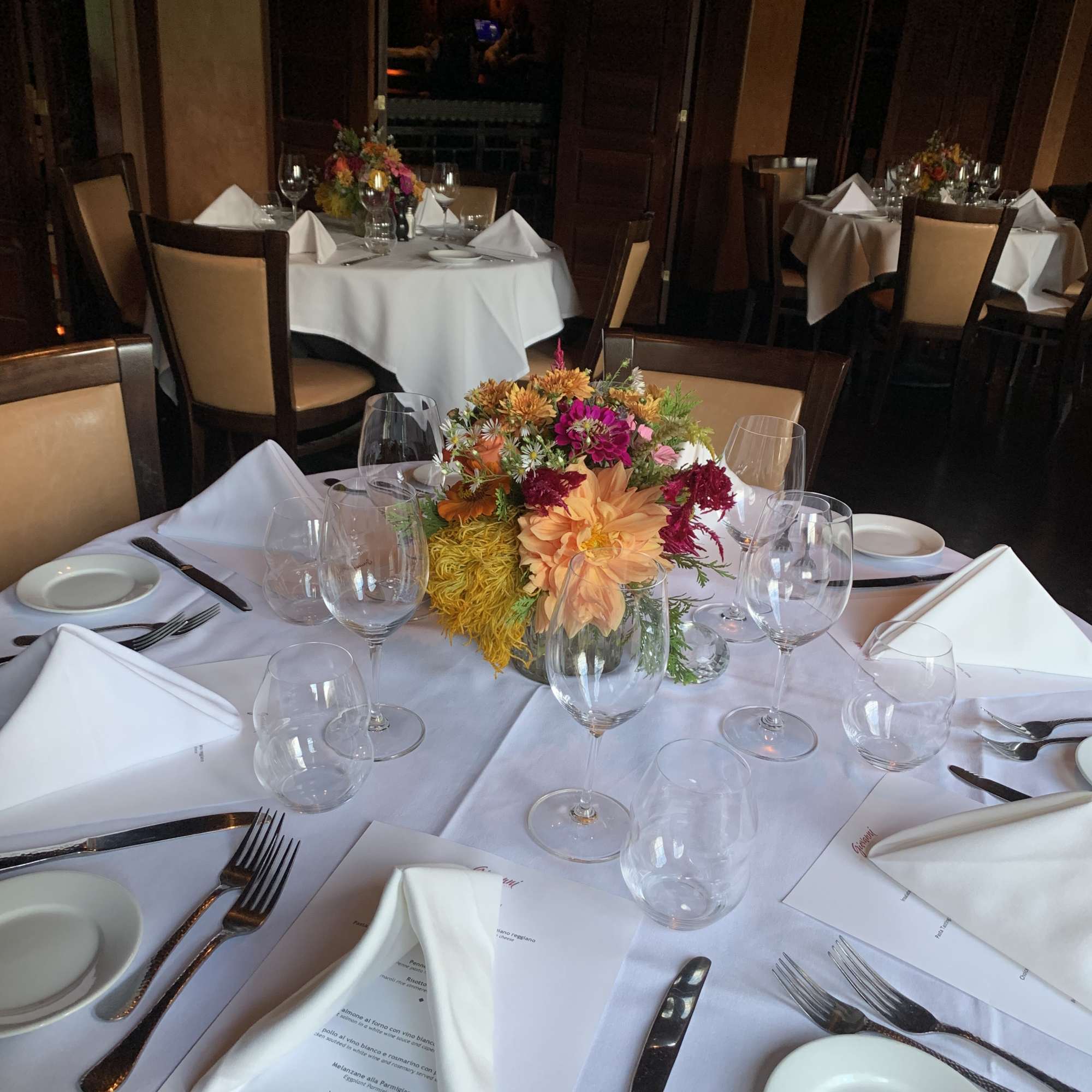 Floral centerpiece on a set dining table with white napkins and glassware