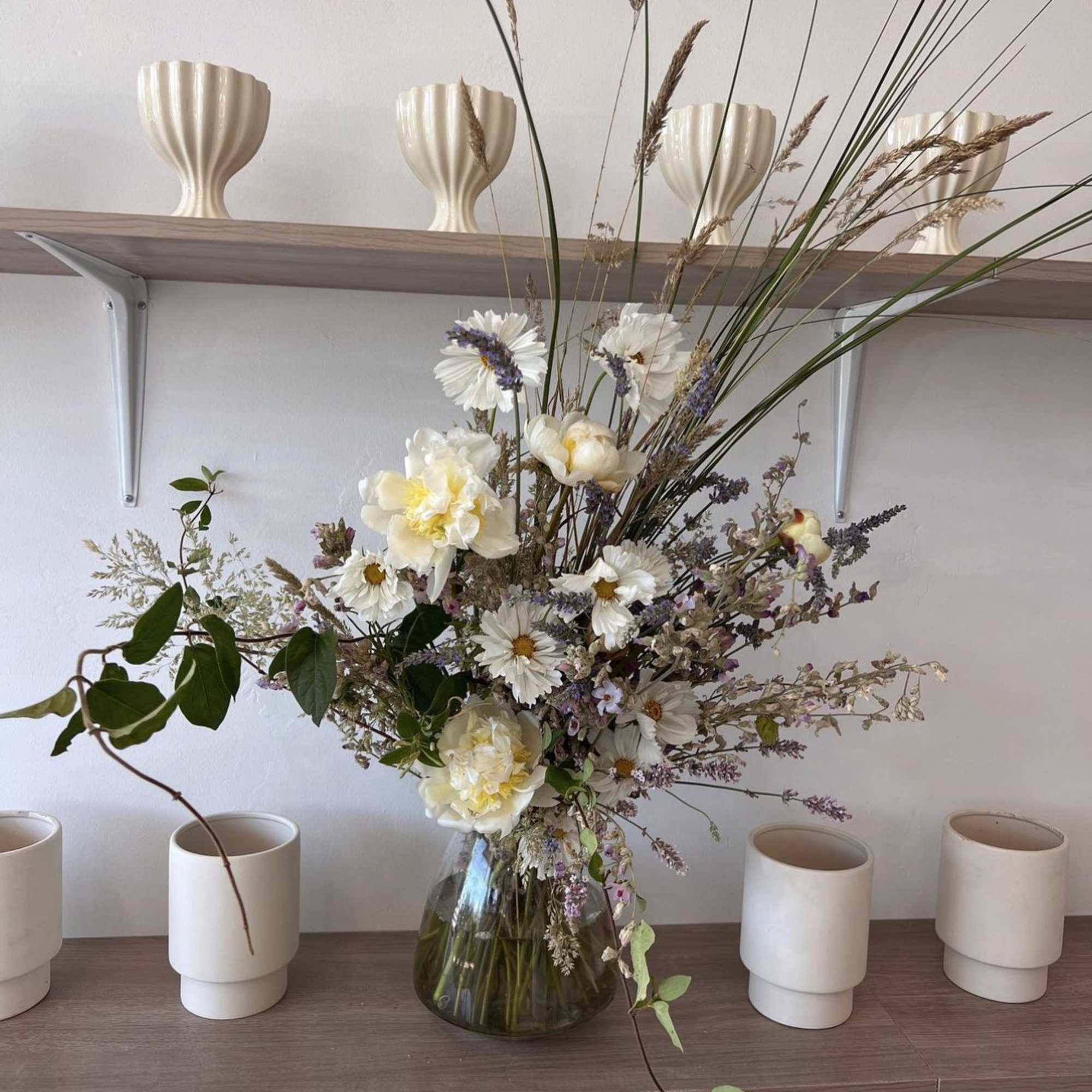 Tall mixed bouquet in a glass vase with white and pale yellow flowers