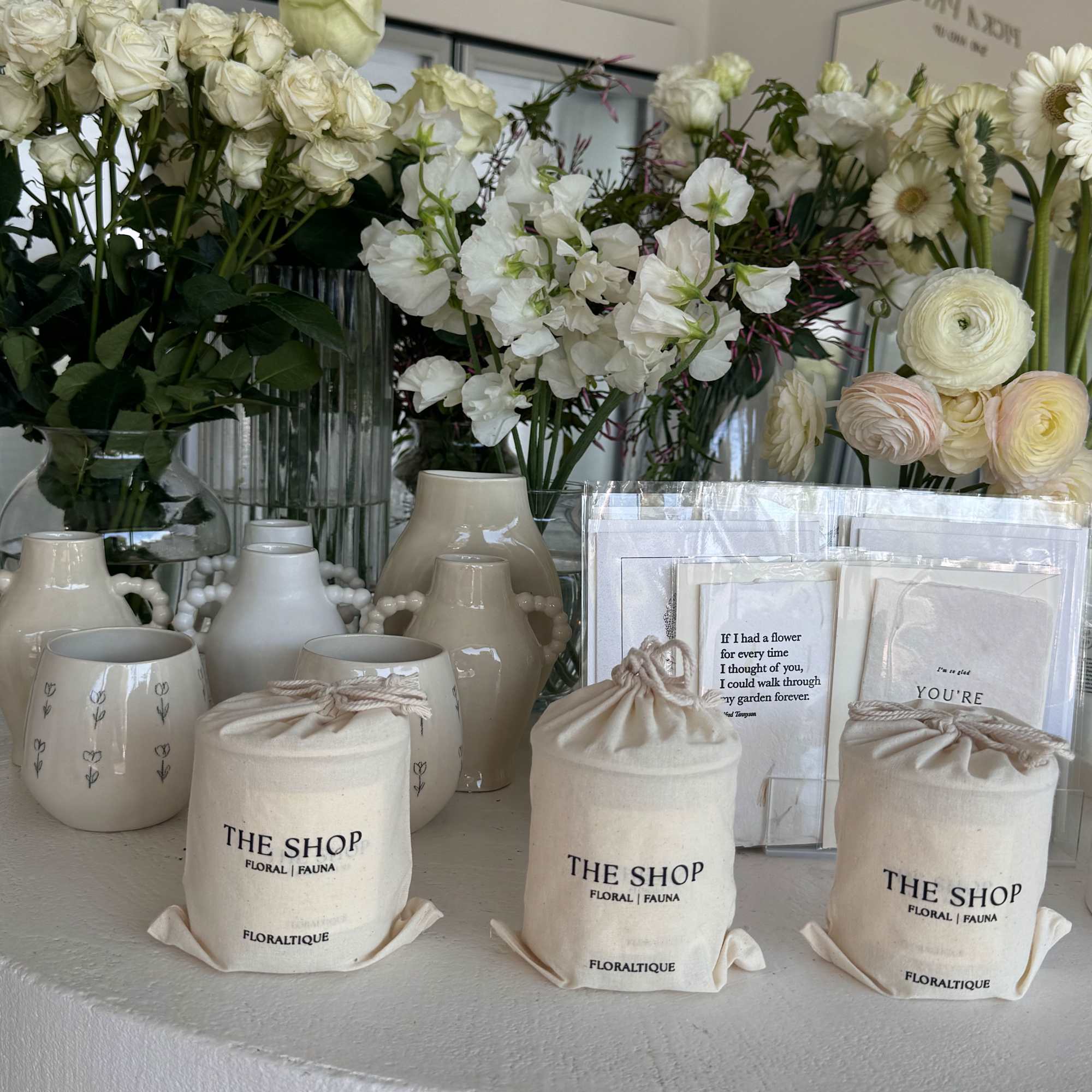 White floral arrangements with roses, ranunculus, and daisies in ceramic vases