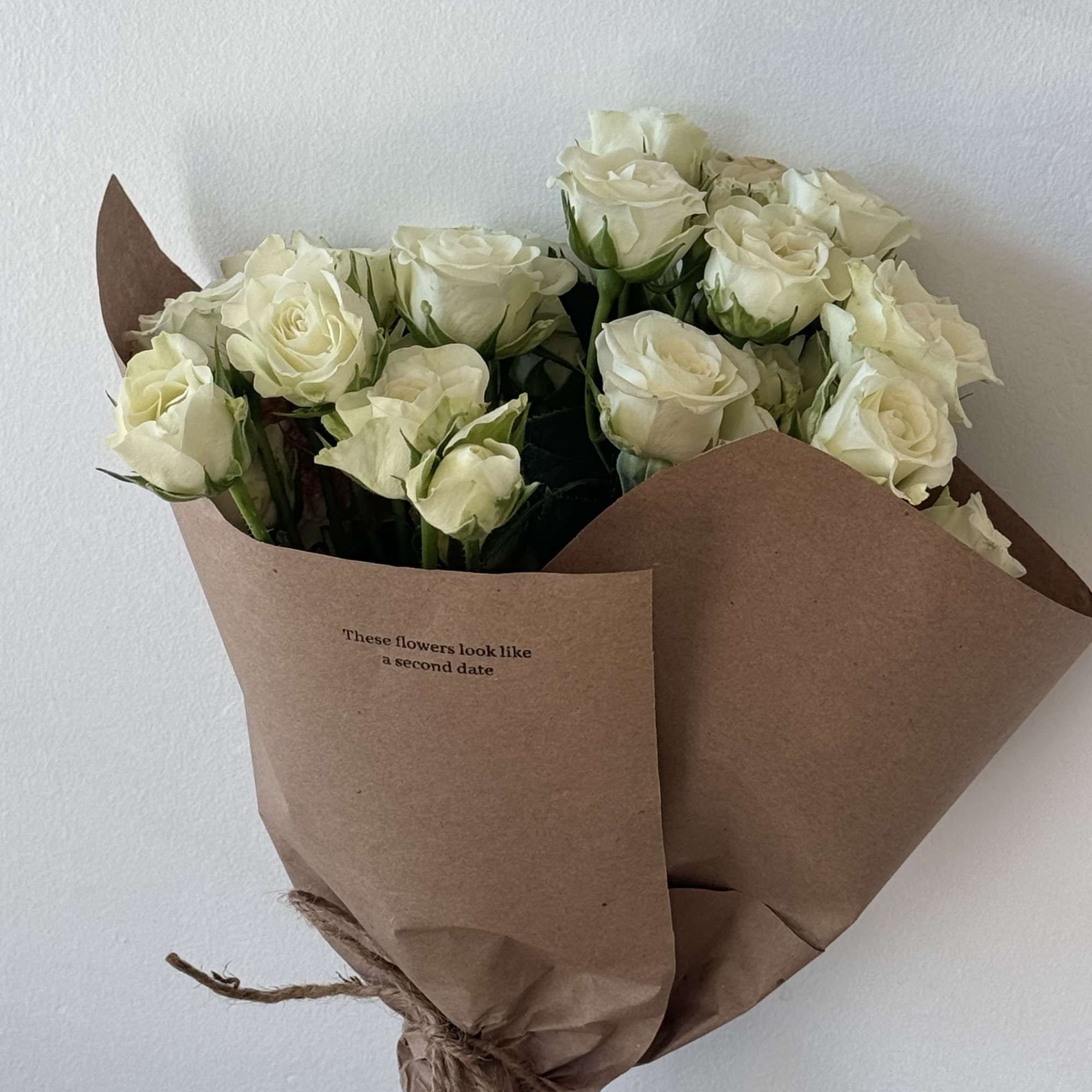 Bouquet of white roses wrapped in brown paper