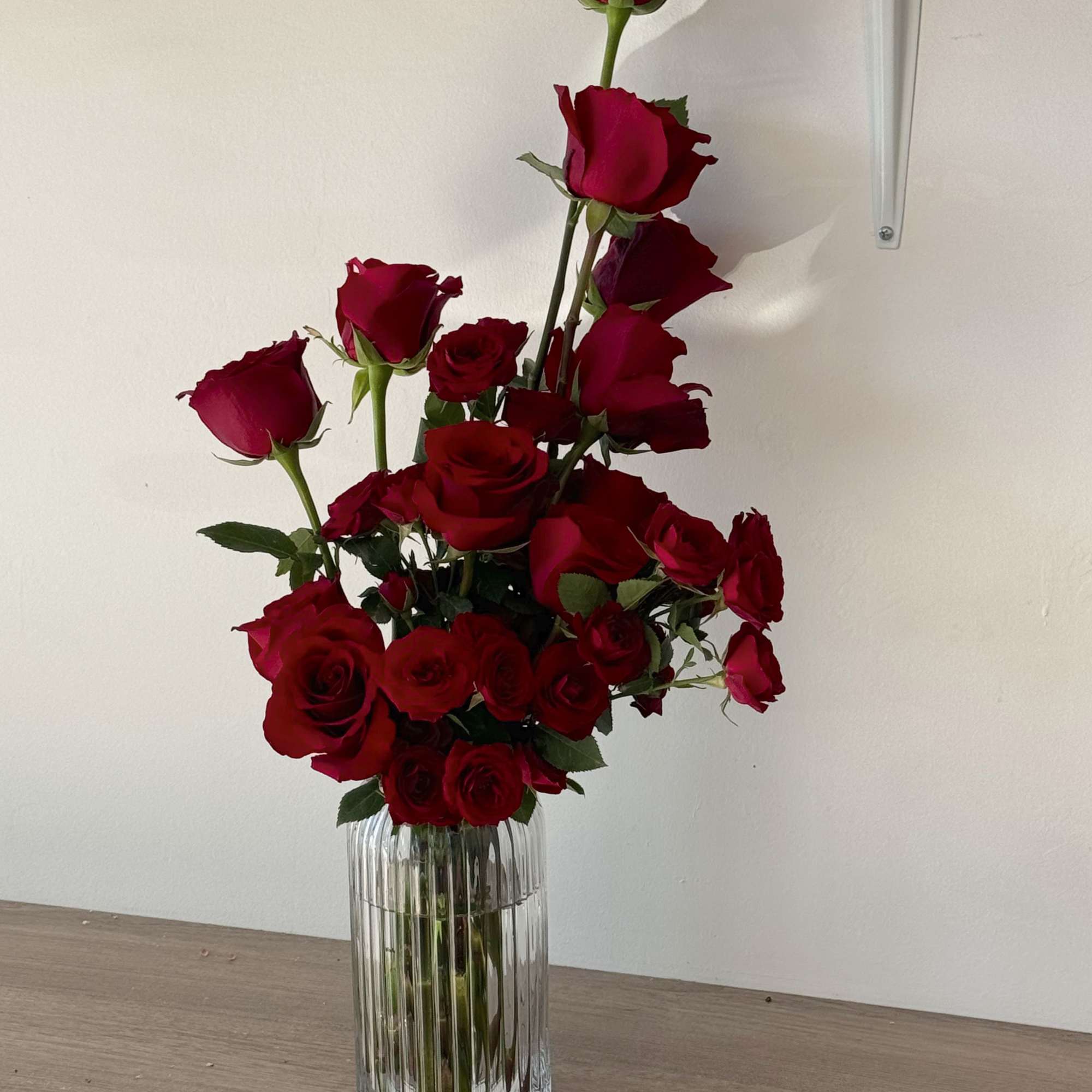 Tall arrangement of red roses in a clear ribbed vase