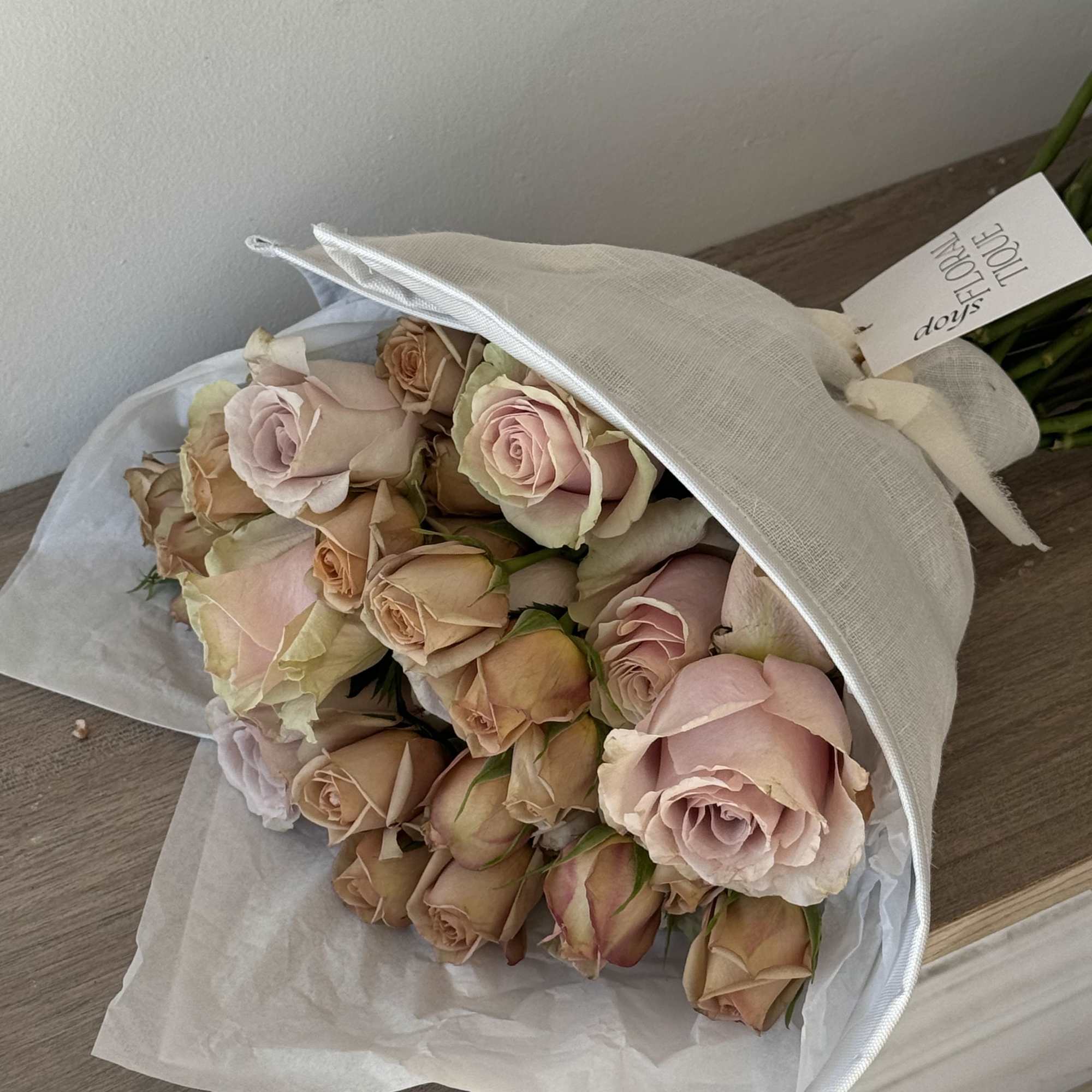 Bouquet of pale pink and peach roses wrapped in white paper