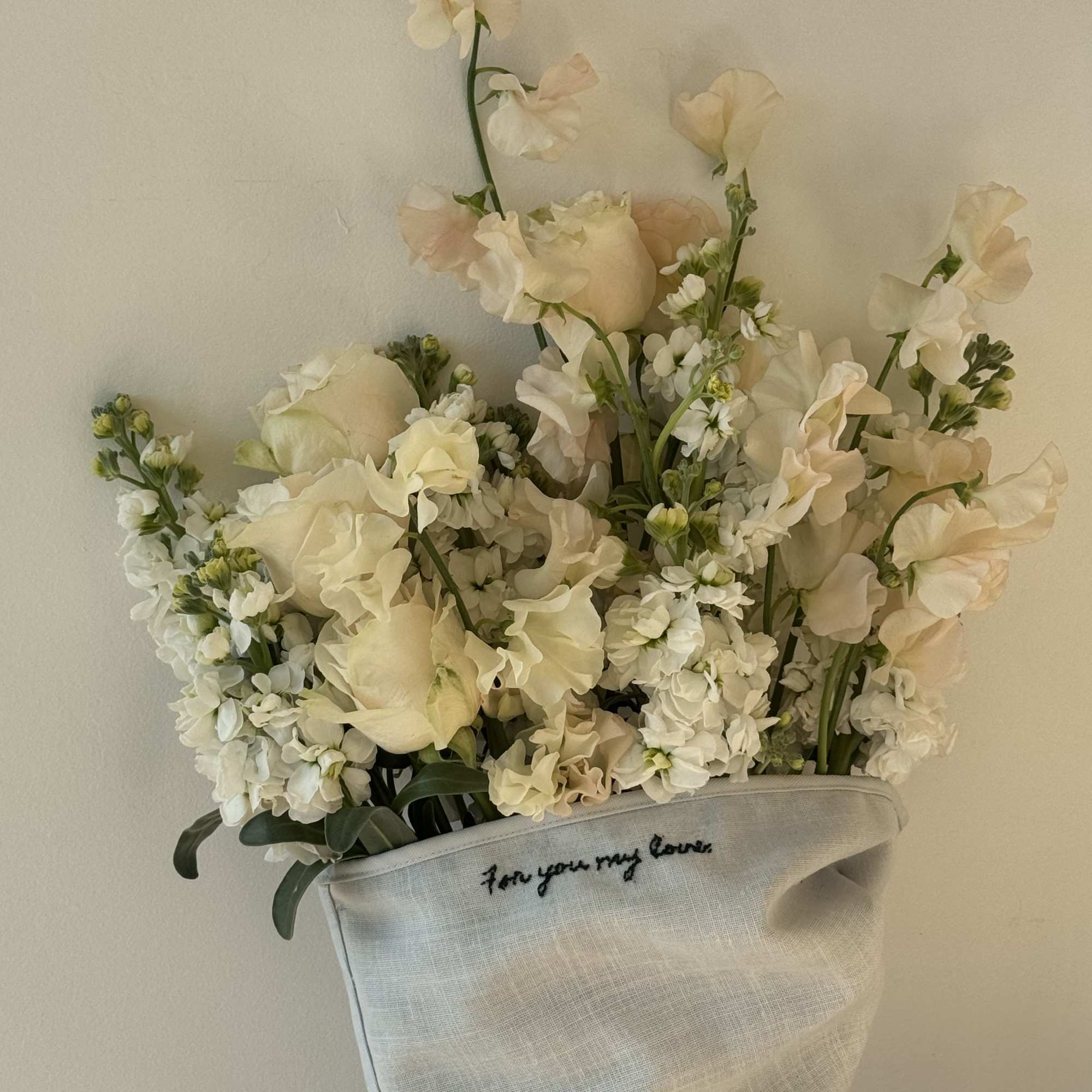 Cream floral bouquet in a light fabric wrap with handwritten text