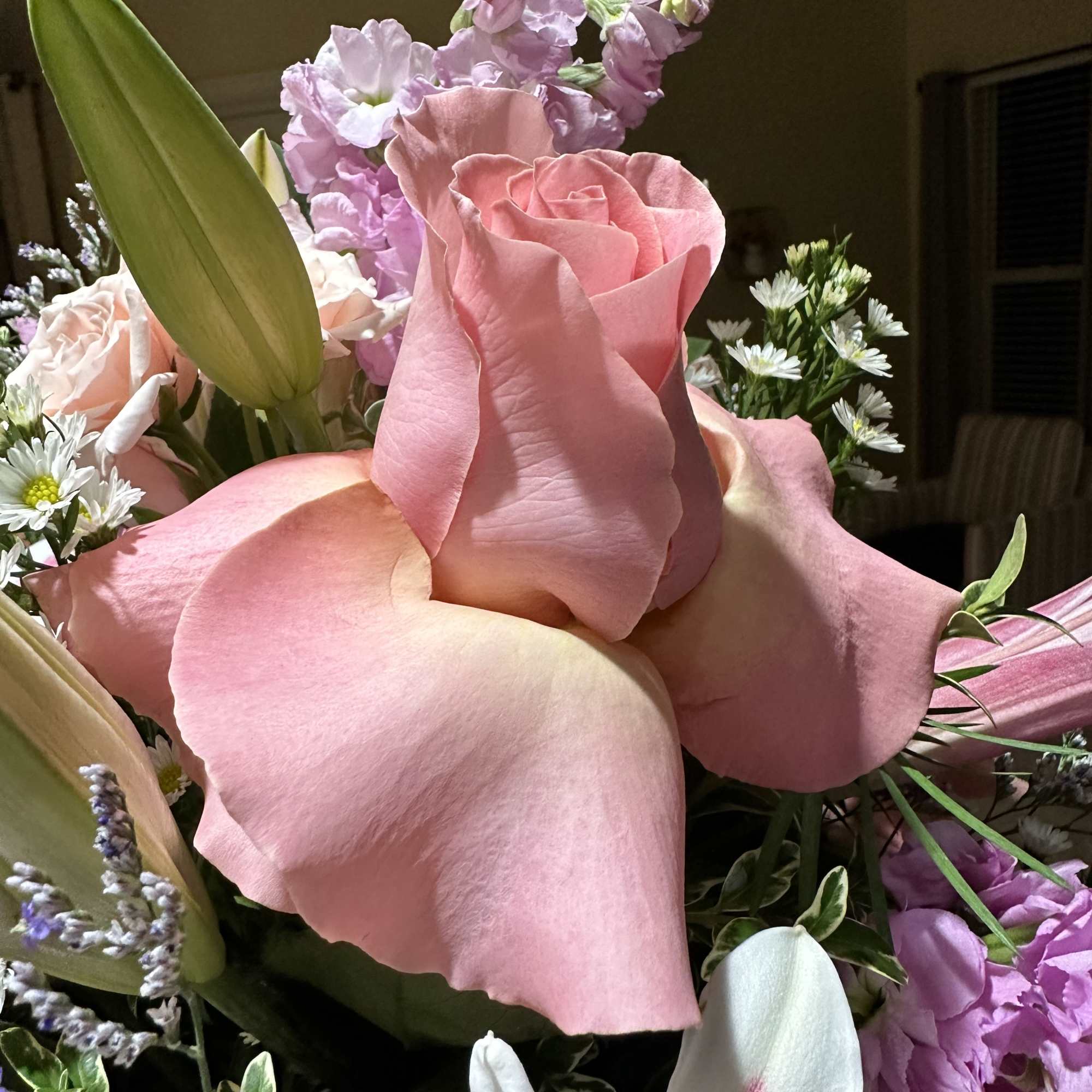 Pink roses with lilies and small purple and white flowers in a bouquet