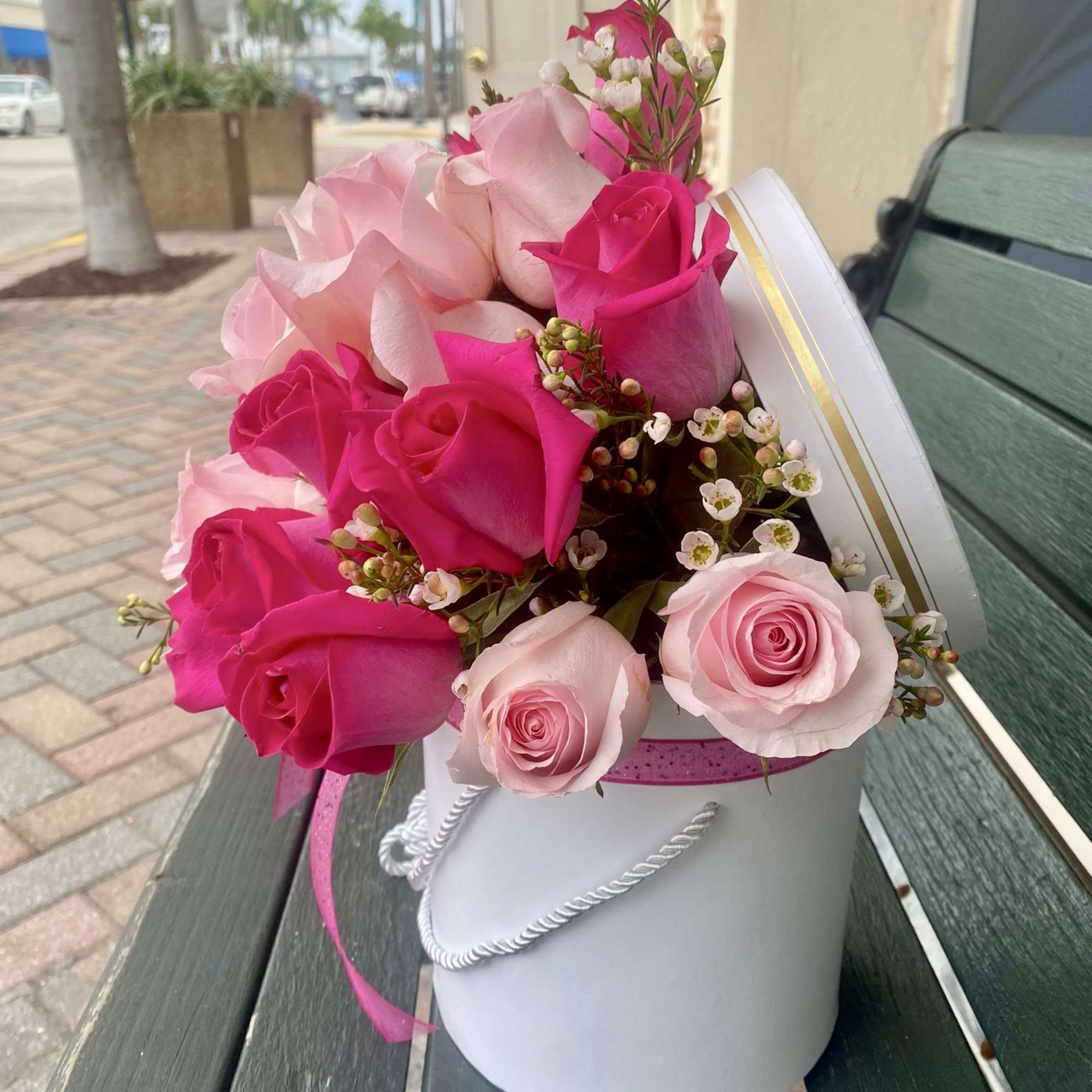 Pink and hot pink roses in a white hatbox with ribbon