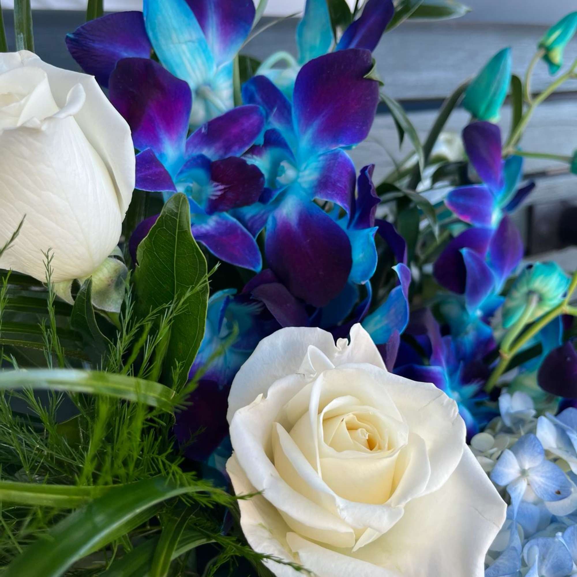 White roses with vivid blue-purple orchids and pale blue hydrangea