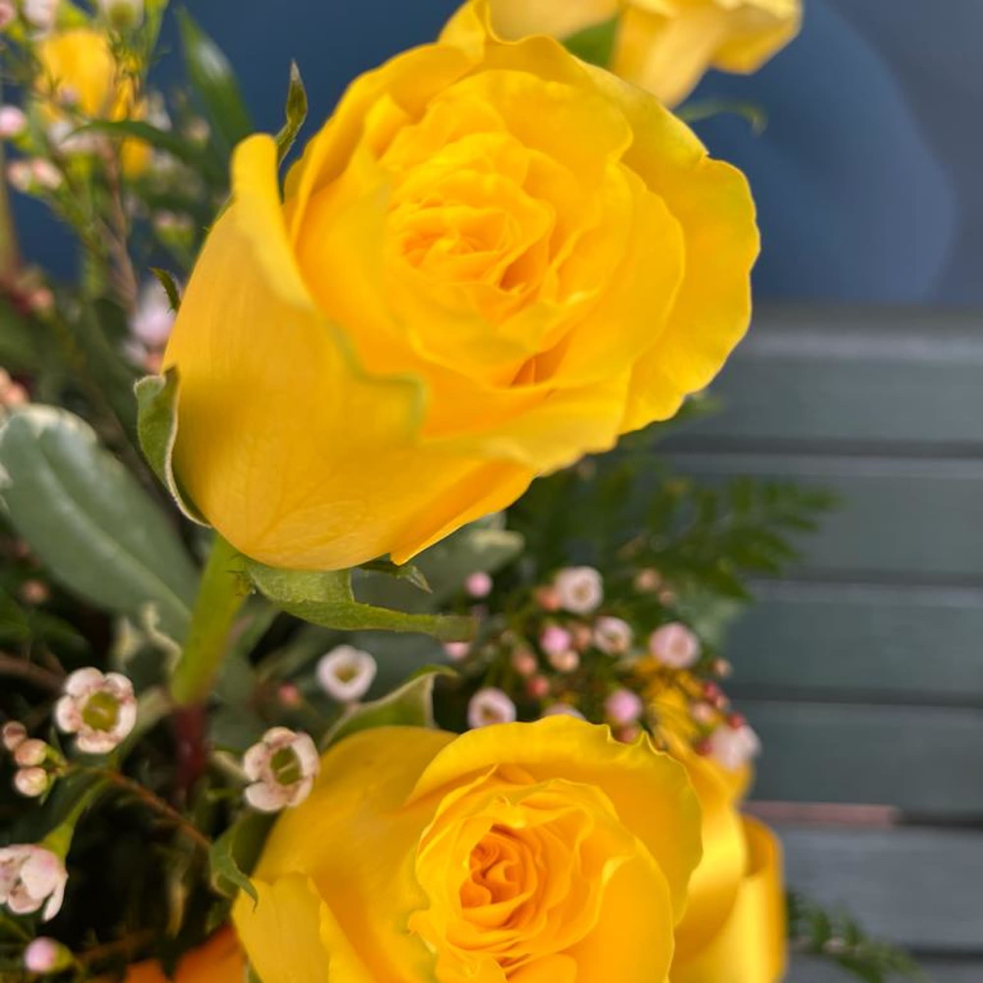 Yellow roses with small pink filler flowers in a bouquet