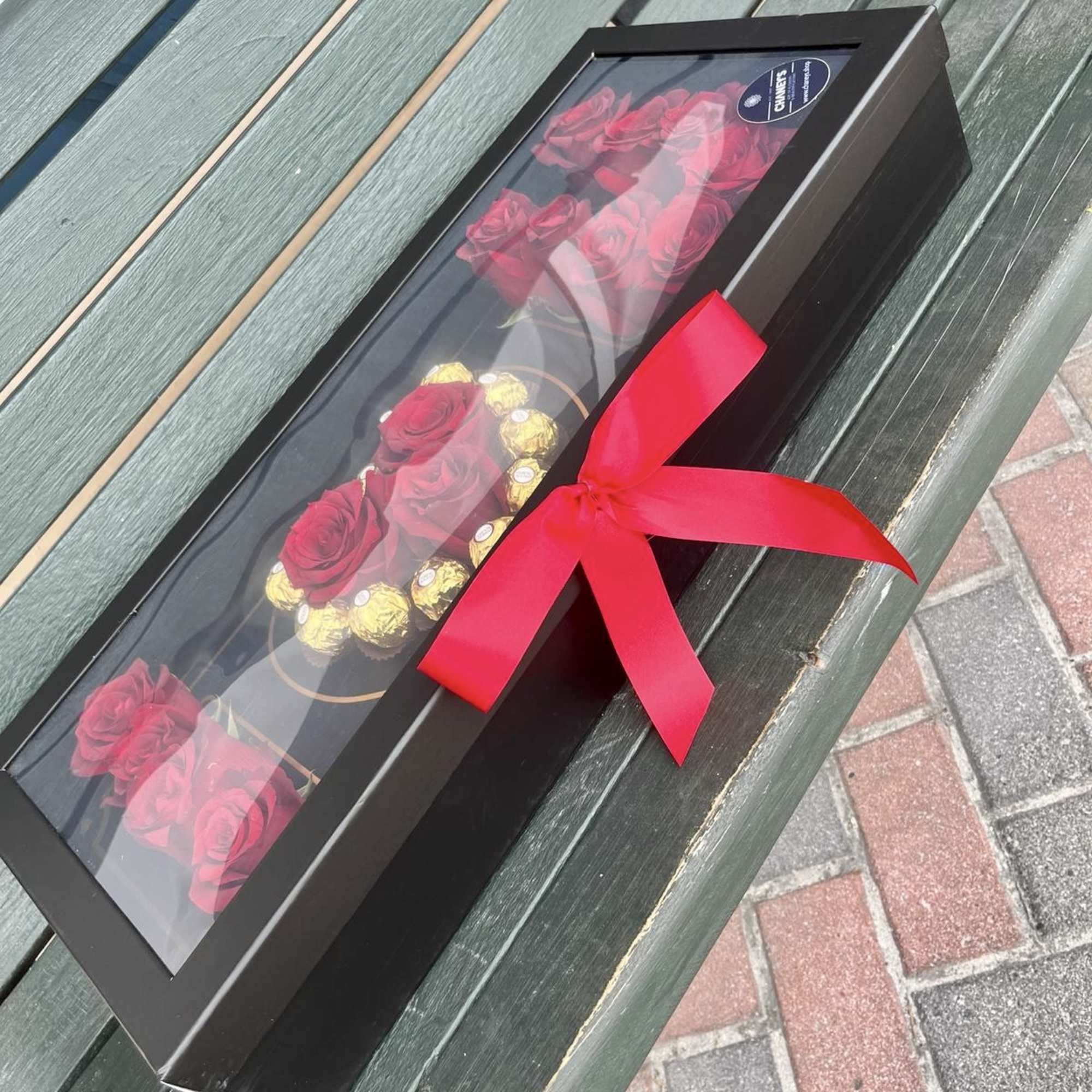 Black gift box with red roses and chocolates tied with a red ribbon