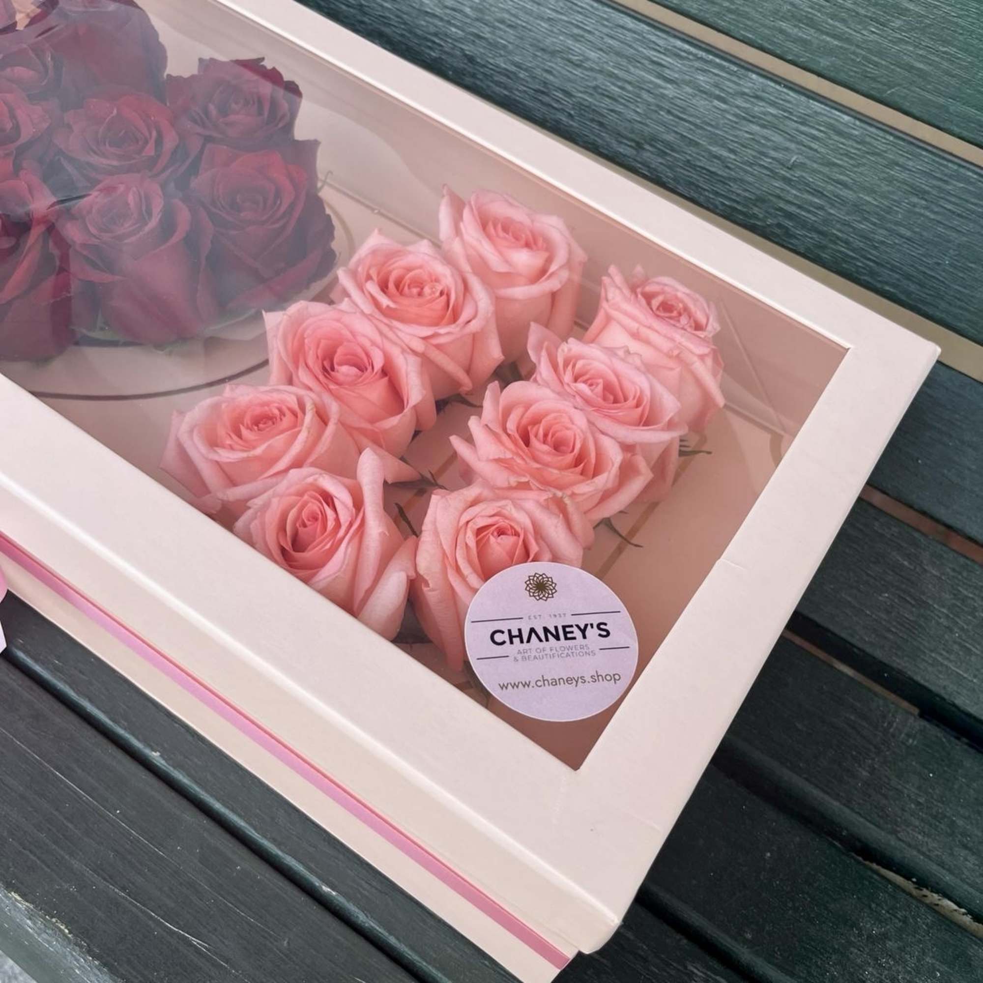 Boxed pink roses and dark red roses in a windowed gift box