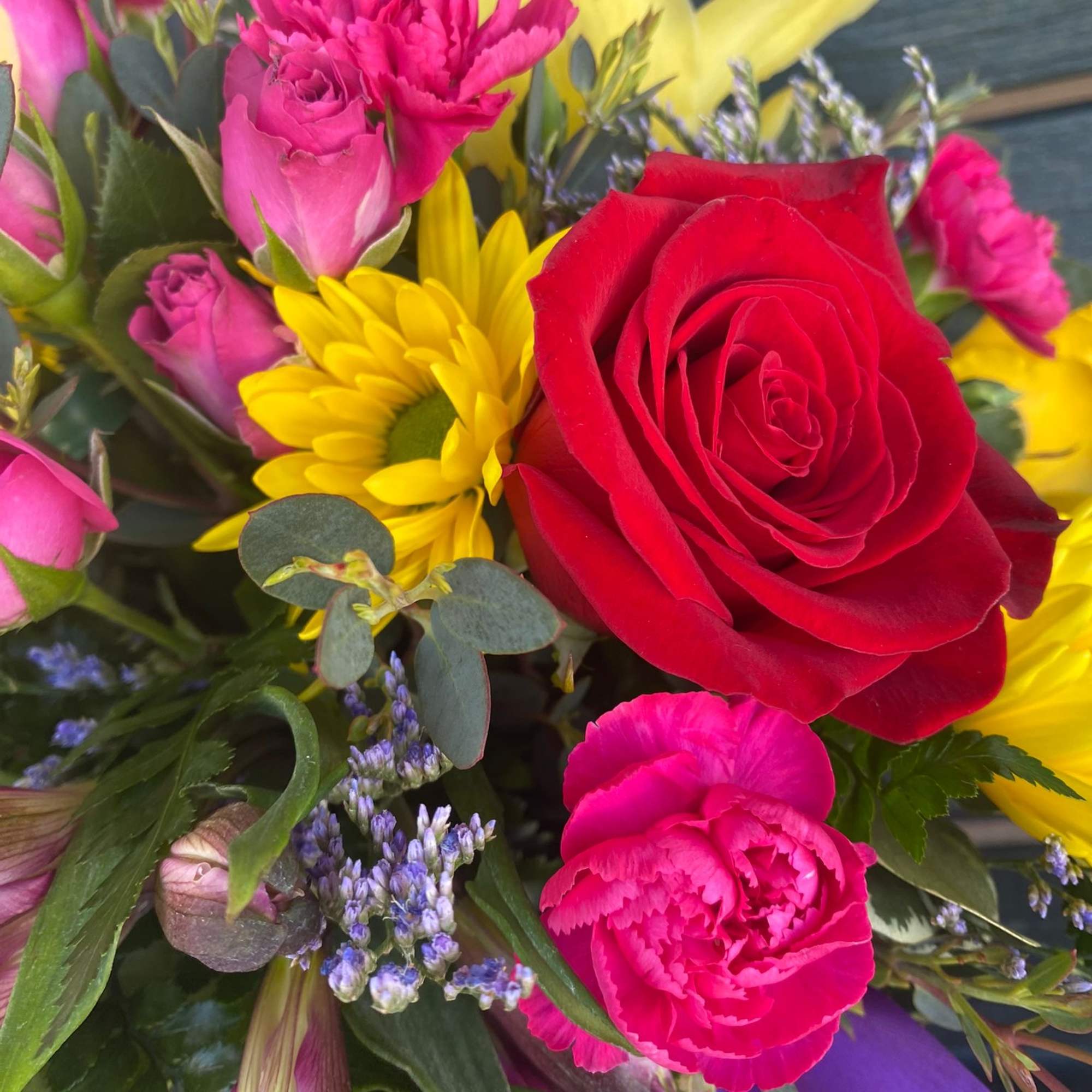 Bouquet of red roses, pink carnations, and yellow daisies