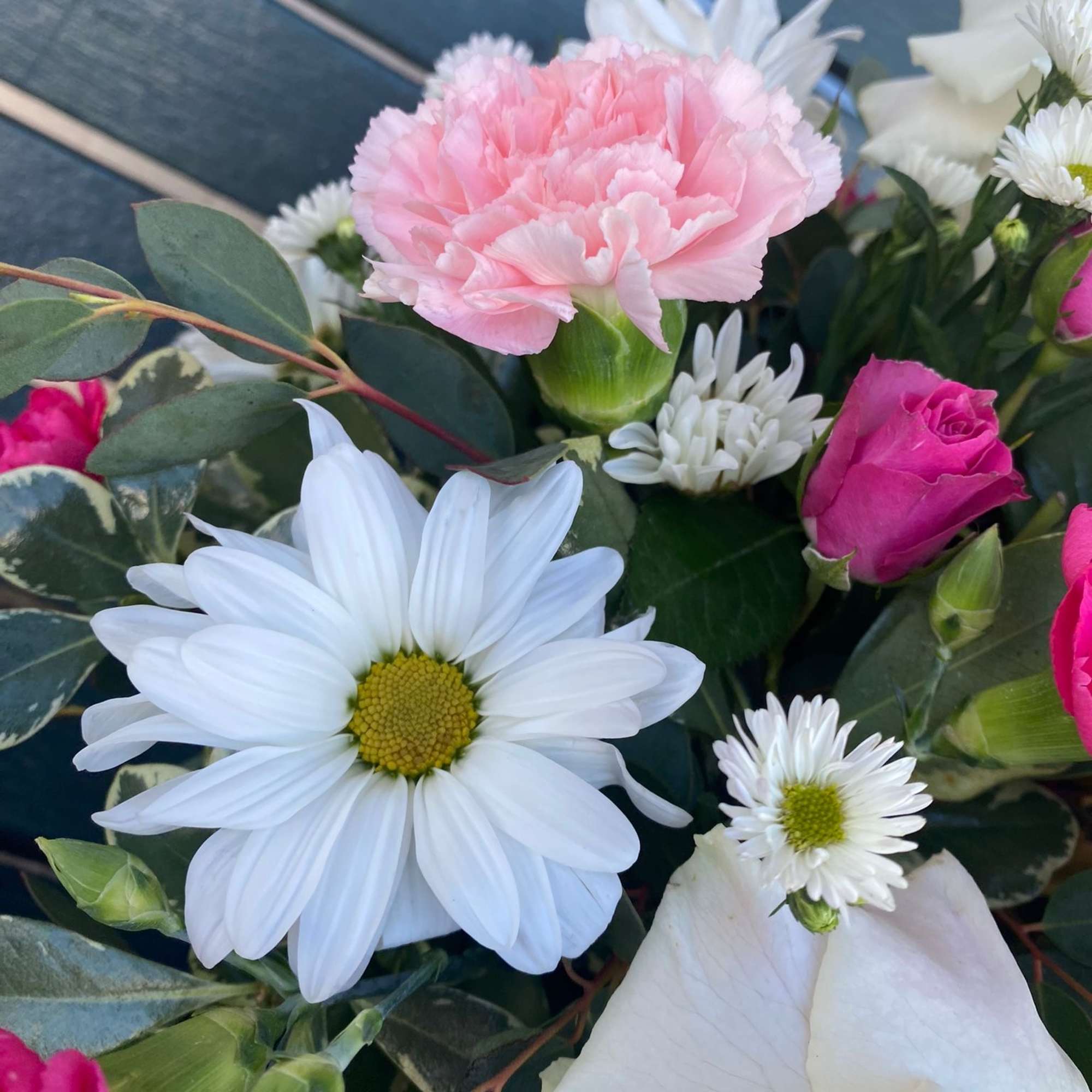Pink carnation and white daisies with roses in a bouquet