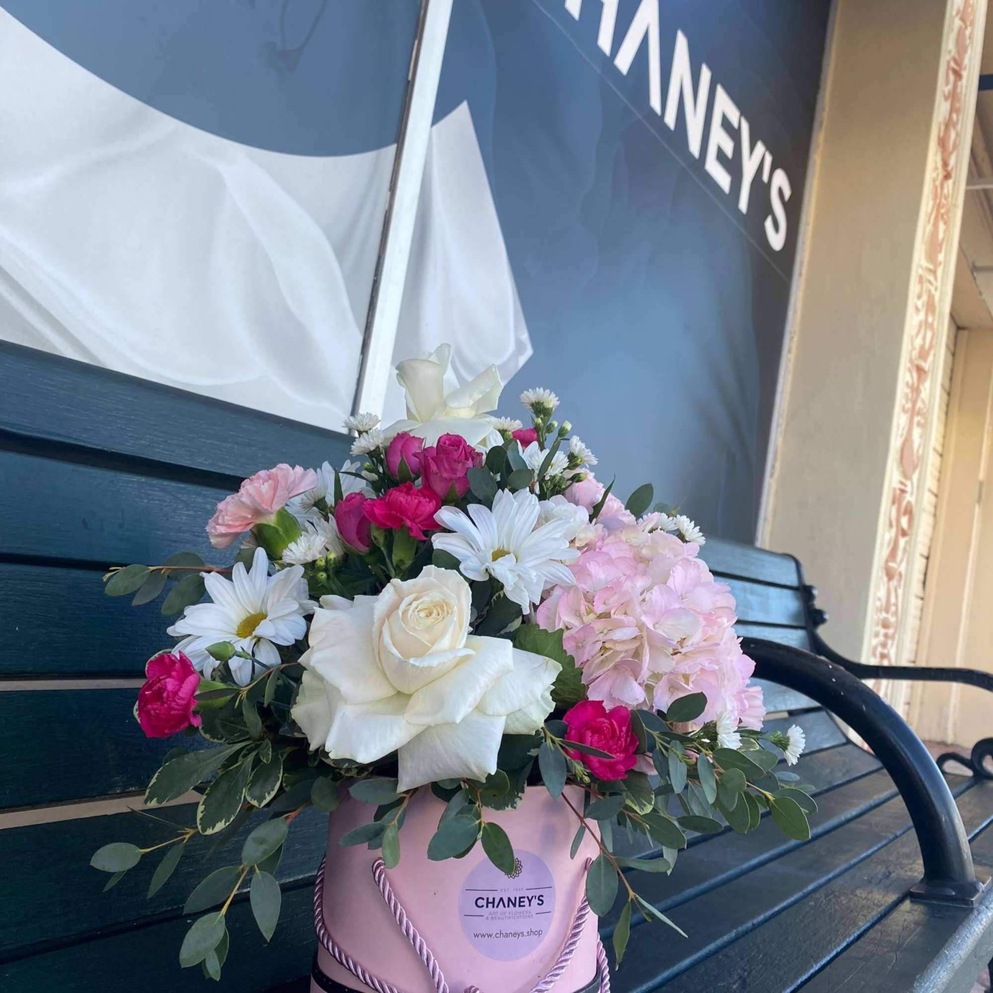 Pink and white flower arrangement in a pink hatbox with rope trim
