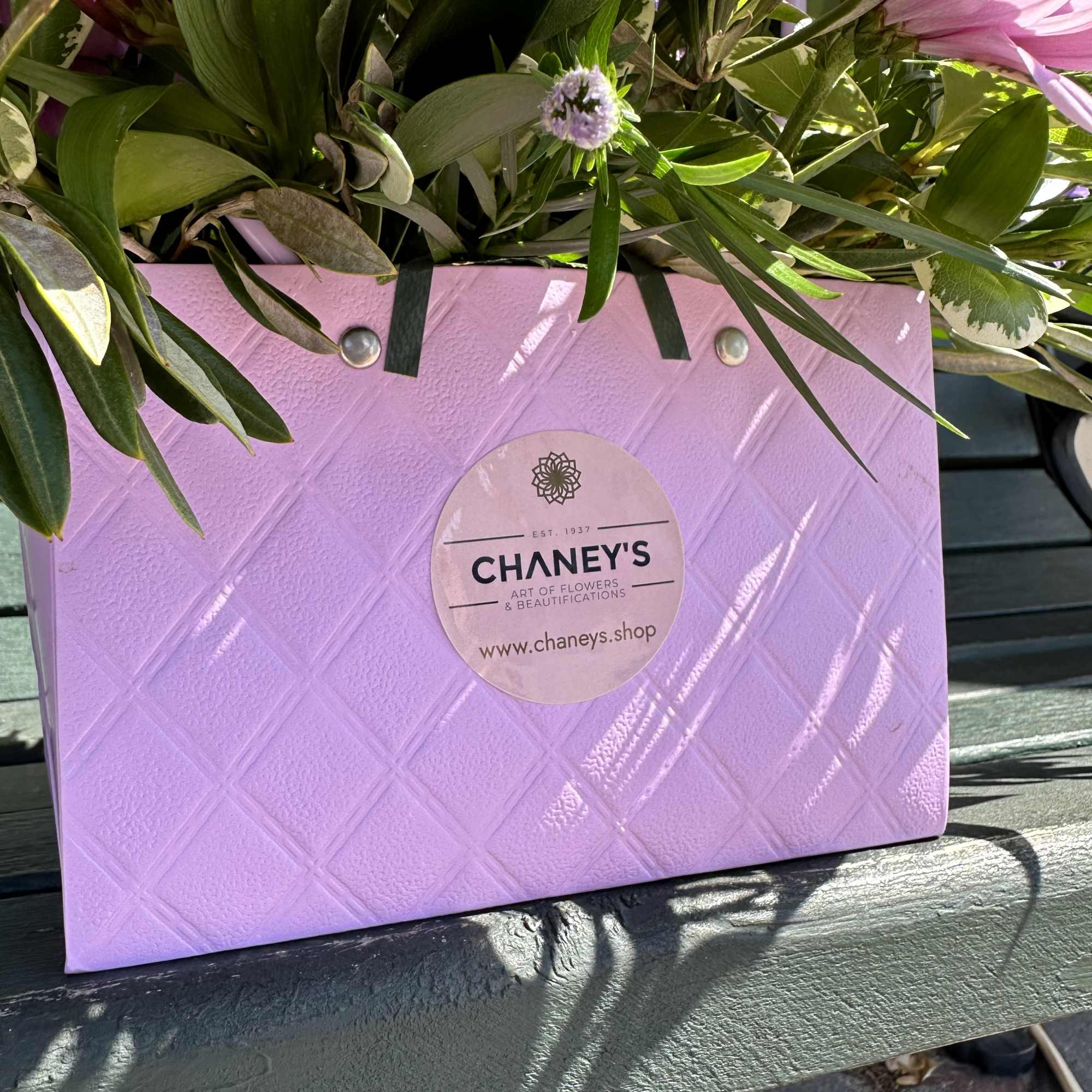 Pink and purple flowers arranged in a lavender gift bag