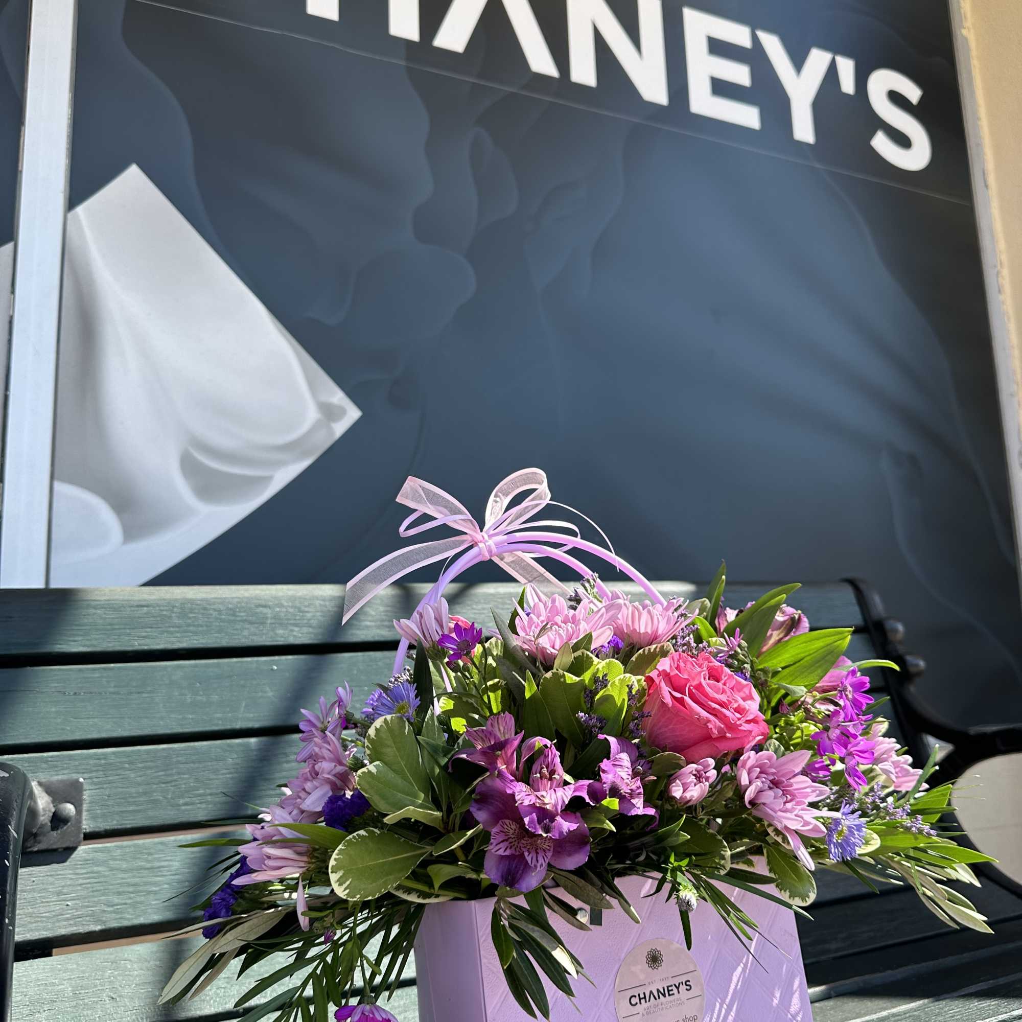 Pink and purple mixed flower arrangement in a lavender gift bag