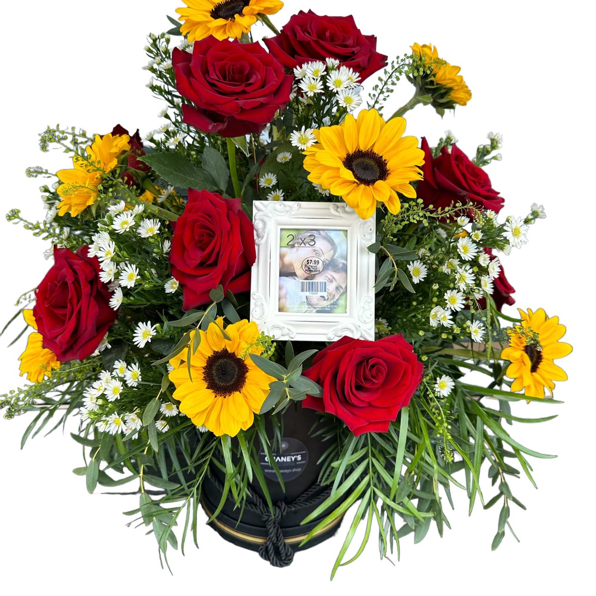 Red roses and yellow sunflowers arranged around a white photo frame in a black container.