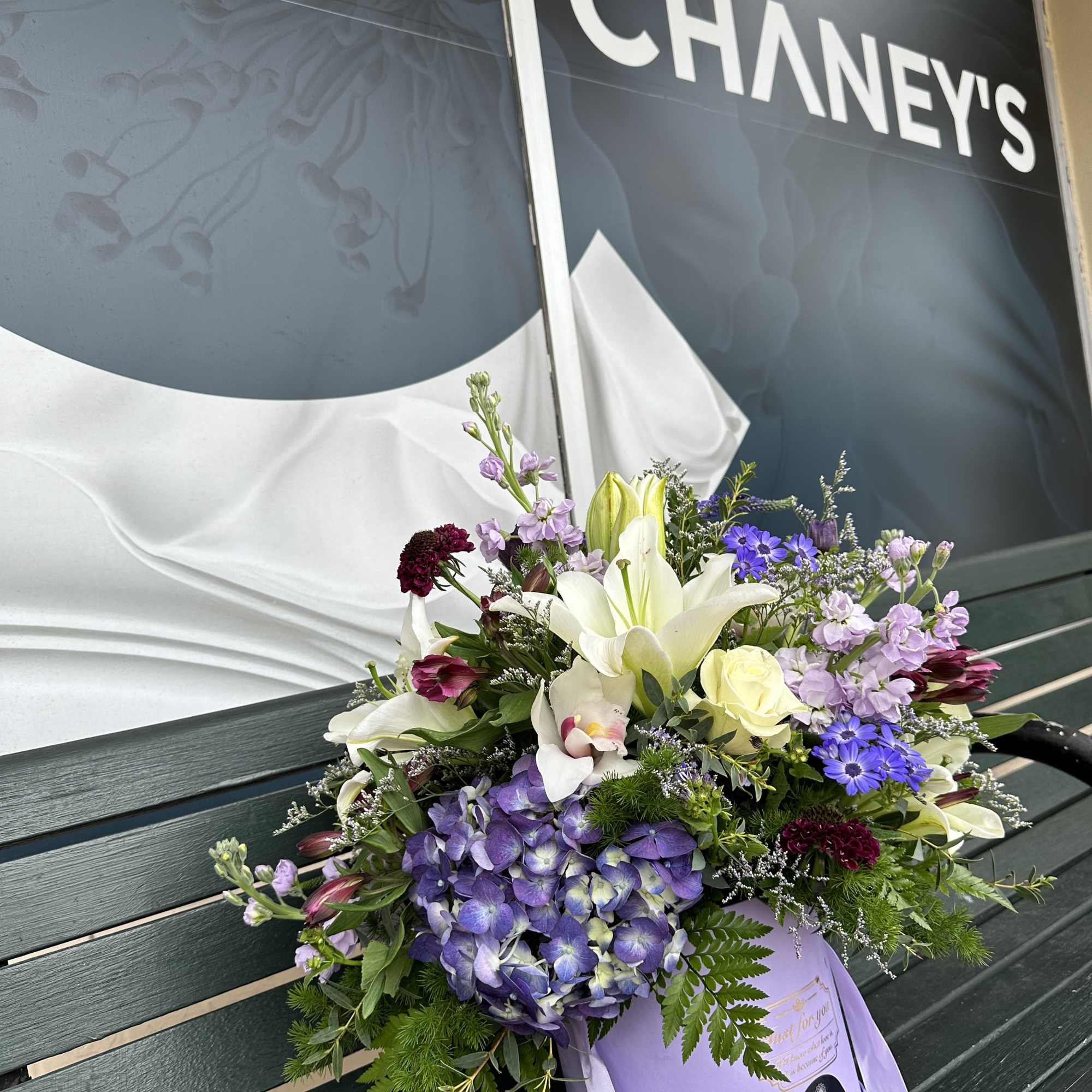 Mixed bouquet with lilies, hydrangea, roses, and purple flowers in a lavender box