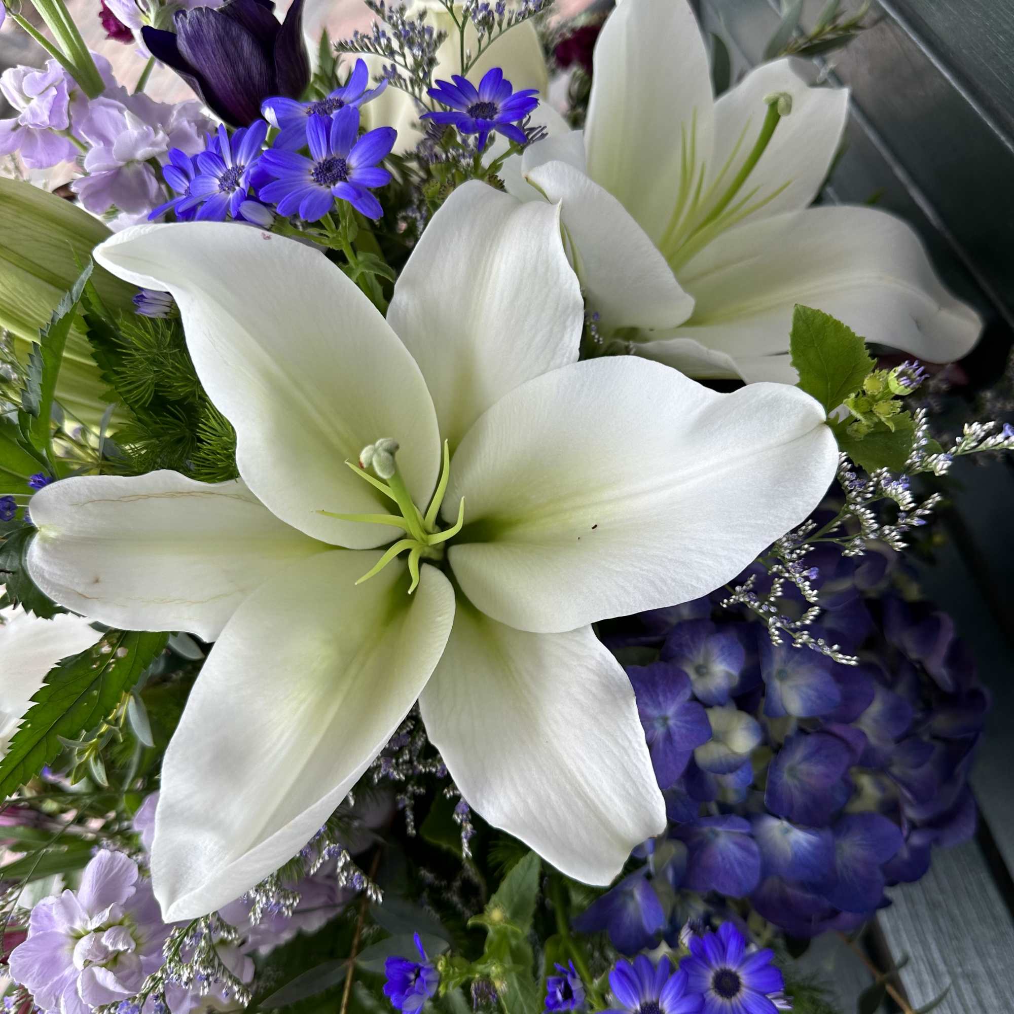White lilies with purple and lavender flowers in a bouquet
