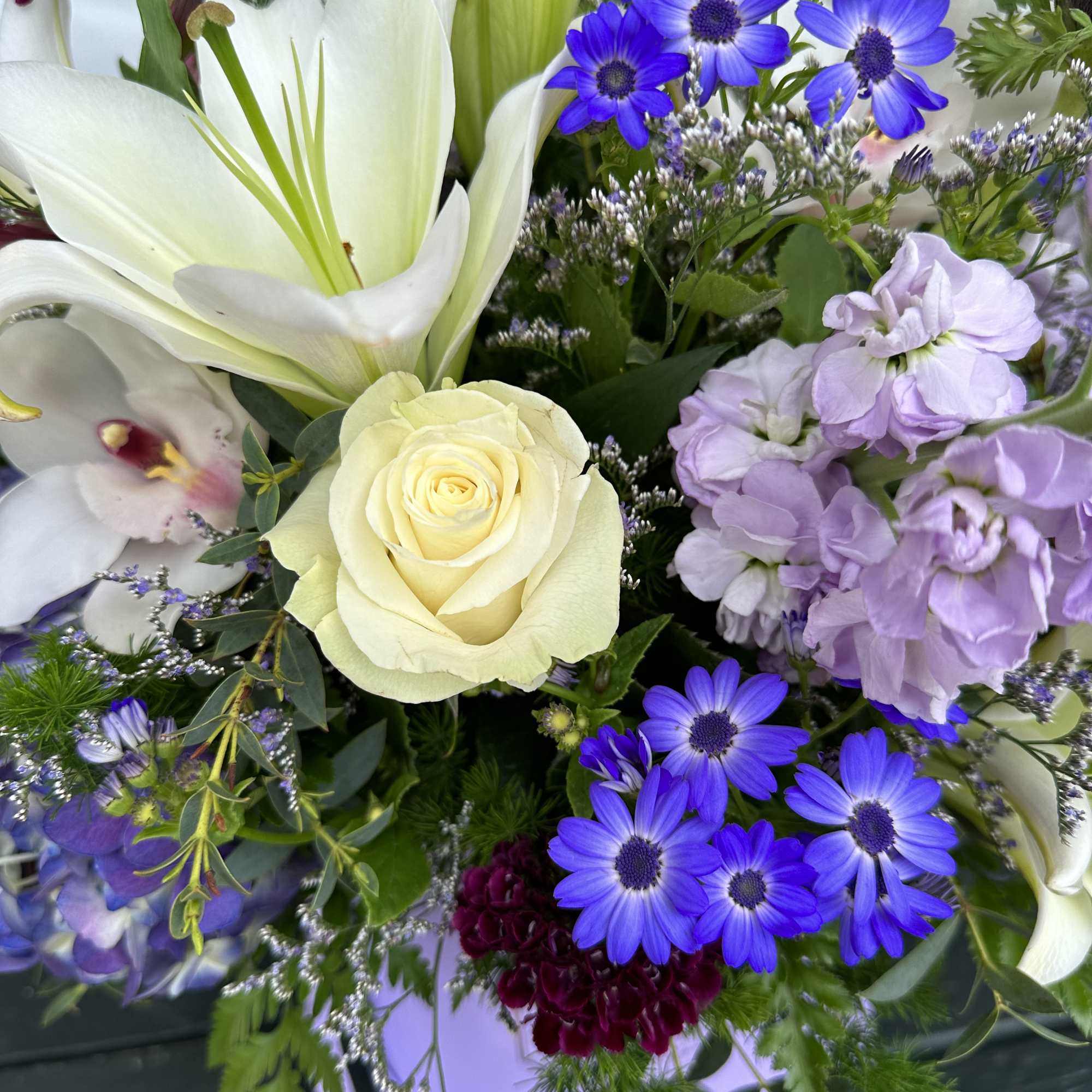 Bouquet of white lilies, cream roses, and purple daisies