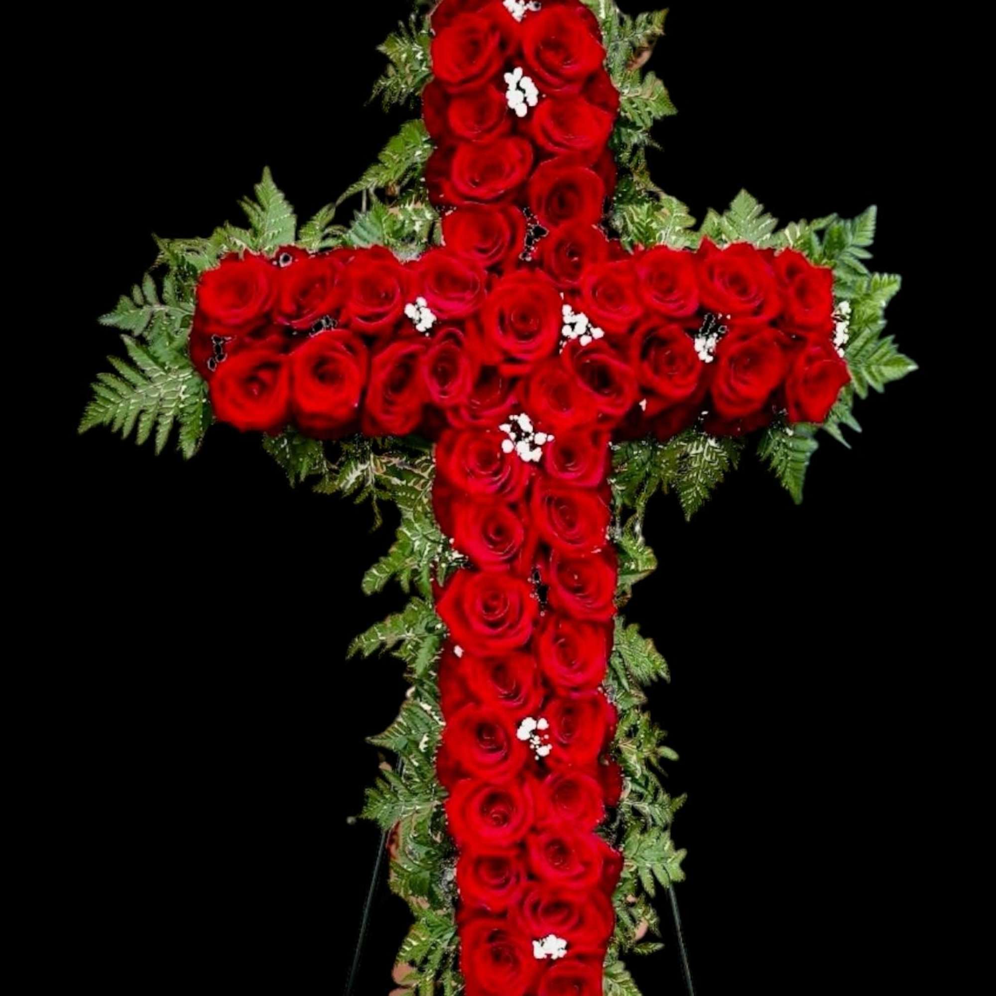 Cross-shaped arrangement of red roses with greenery on a black background