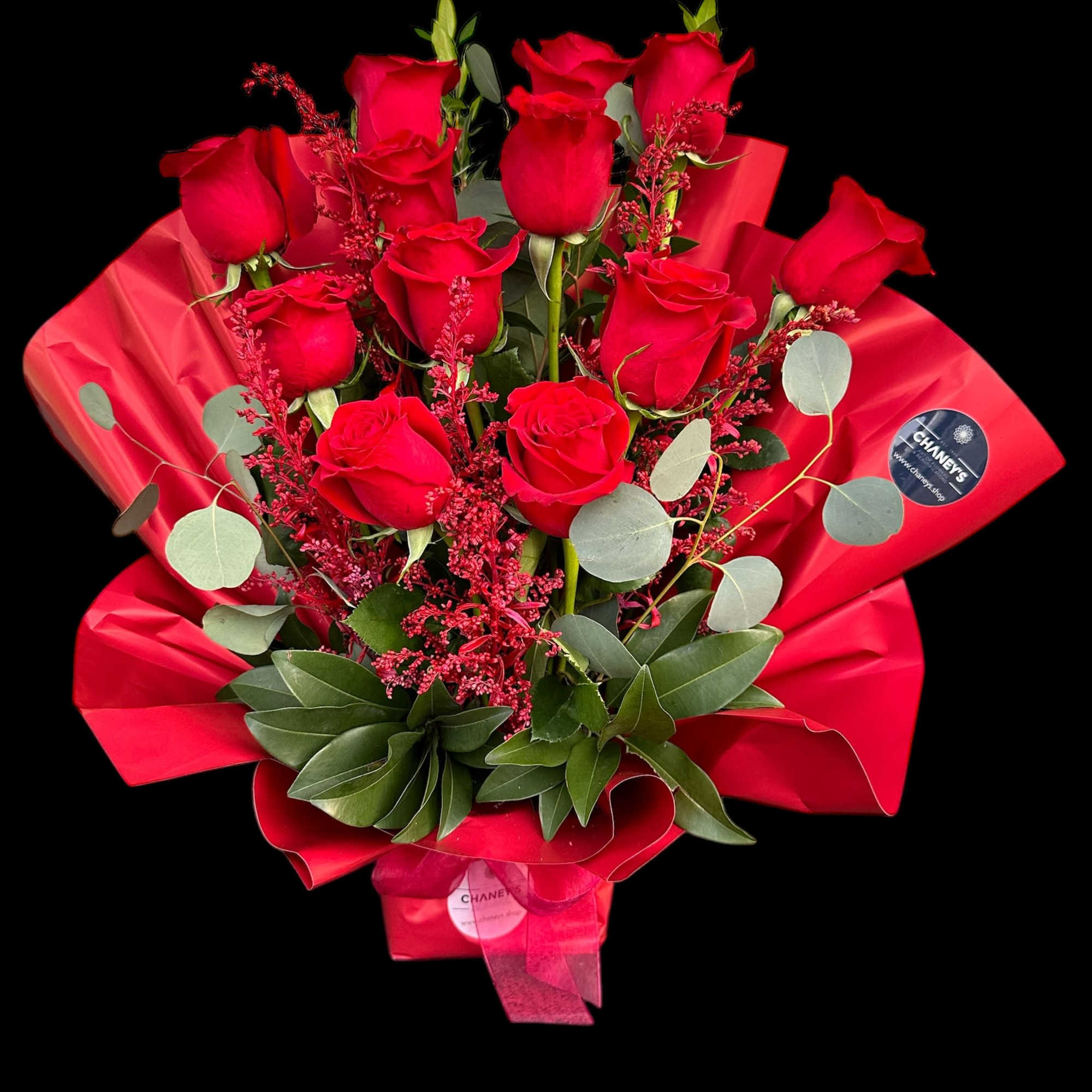 Bouquet of red roses wrapped in red paper with greenery