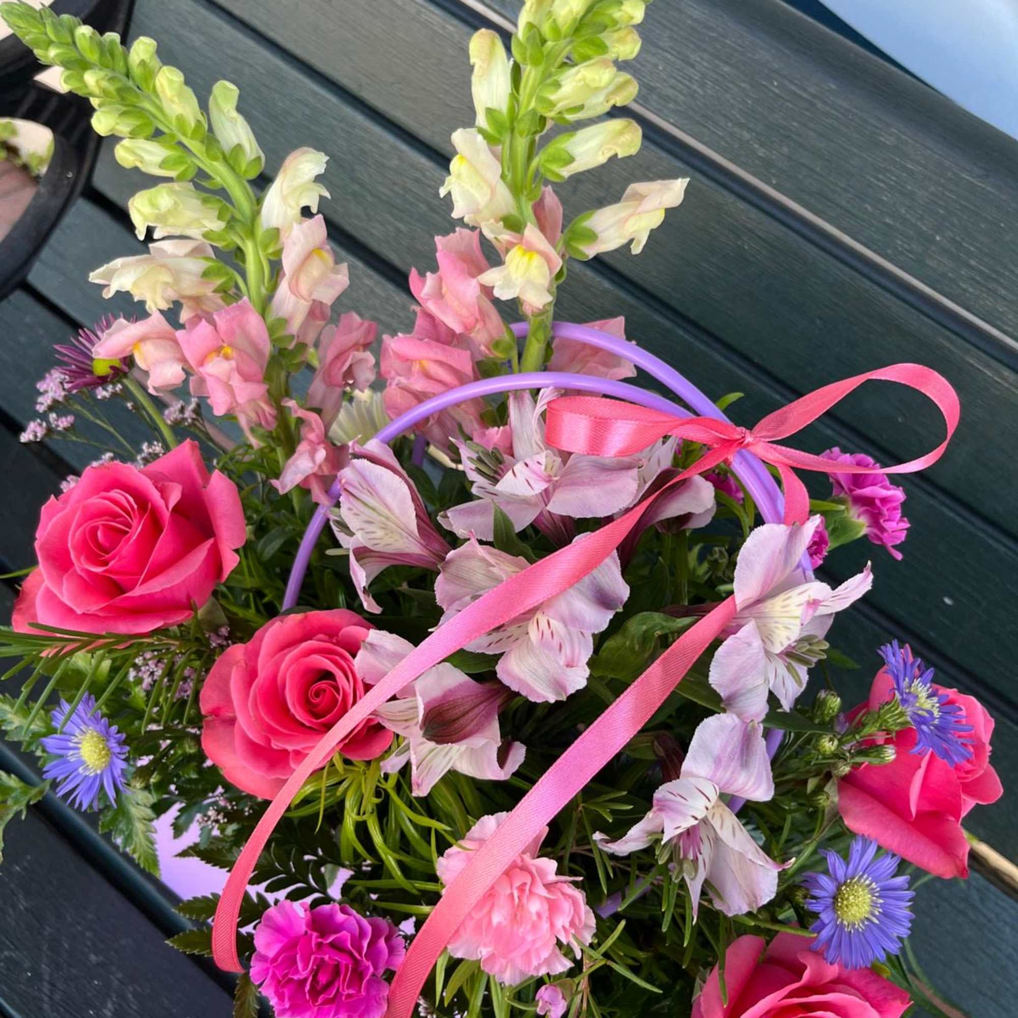 Pink roses and mixed flowers in a basket with ribbon handles