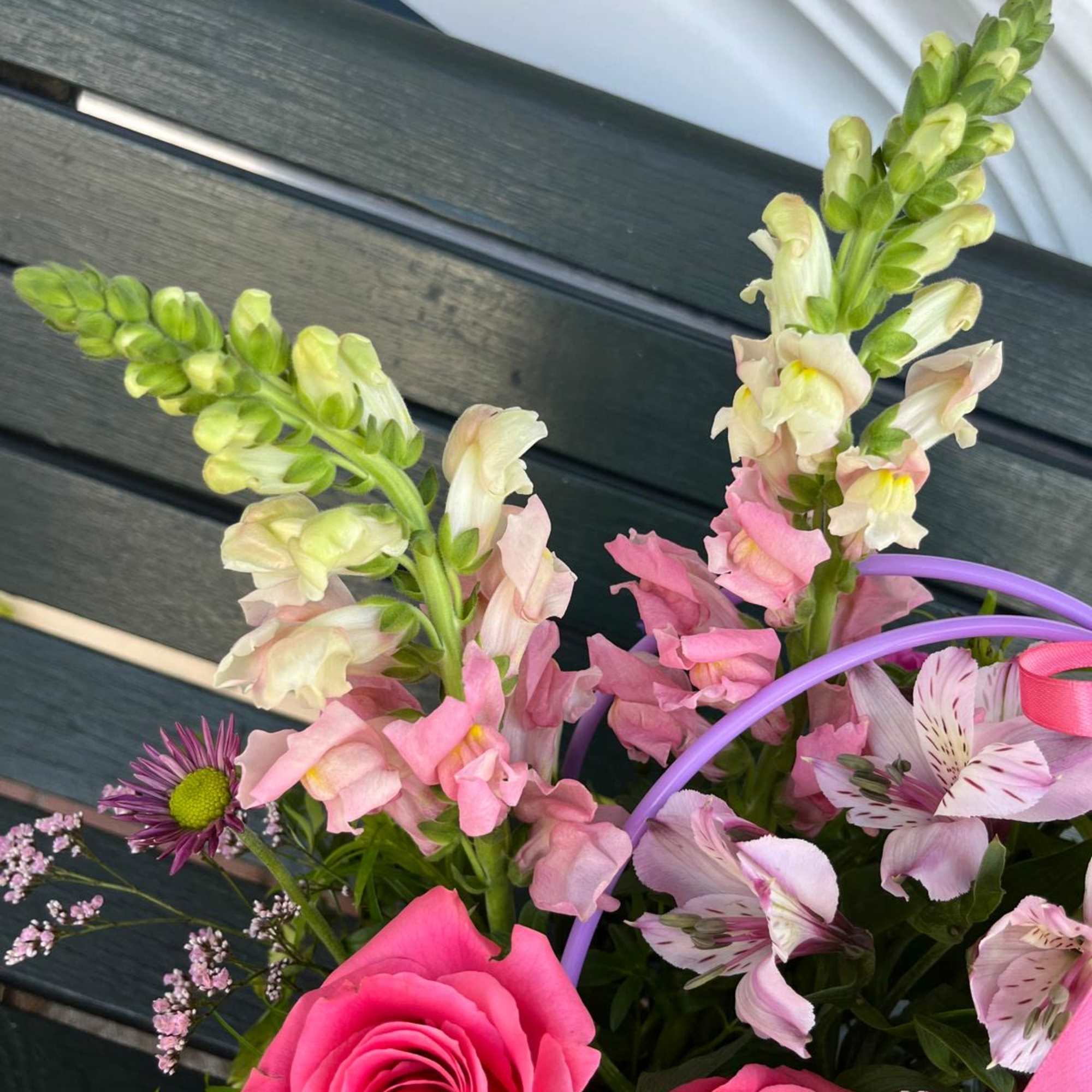 Bouquet of pink roses, snapdragons, and alstroemeria with a purple handle