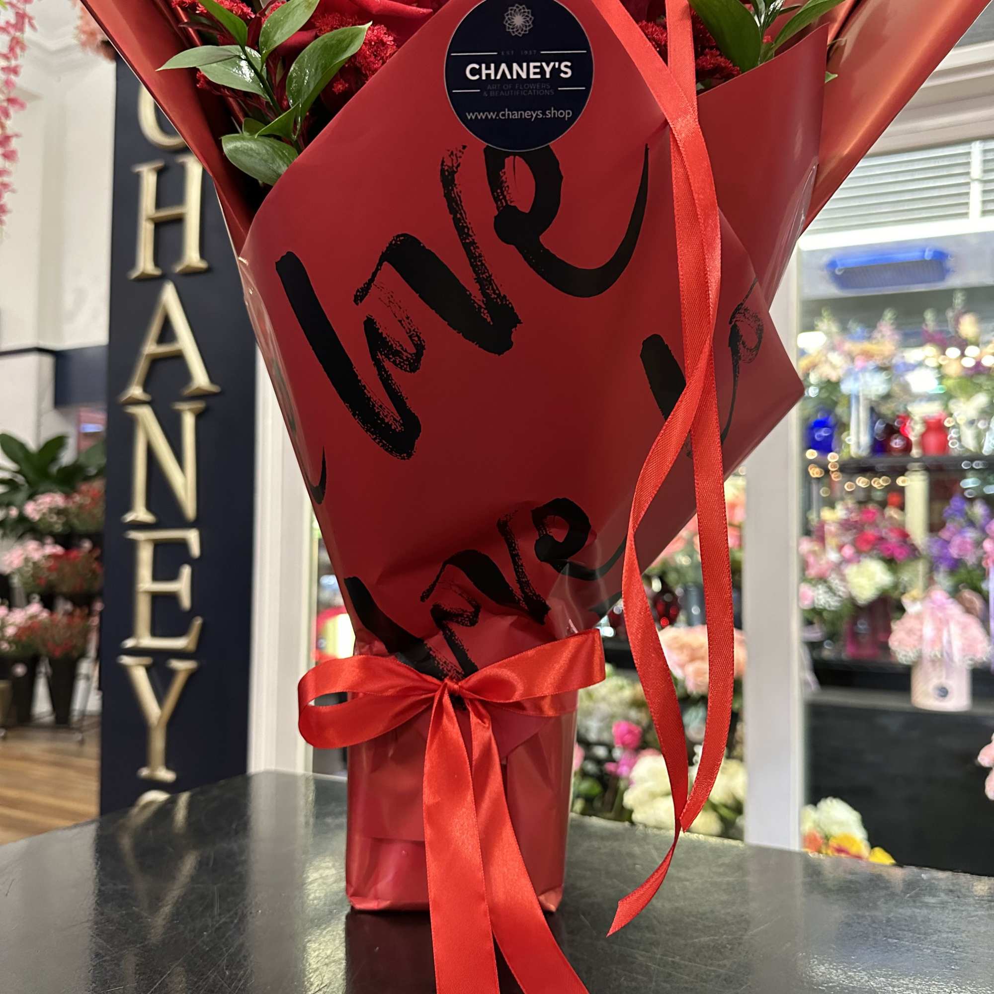 Red rose bouquet wrapped in red paper with a ribbon