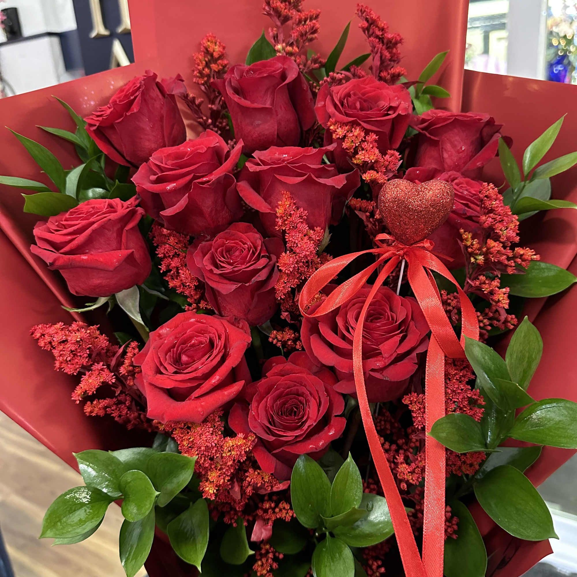 Bouquet of red roses with red filler and a heart pick