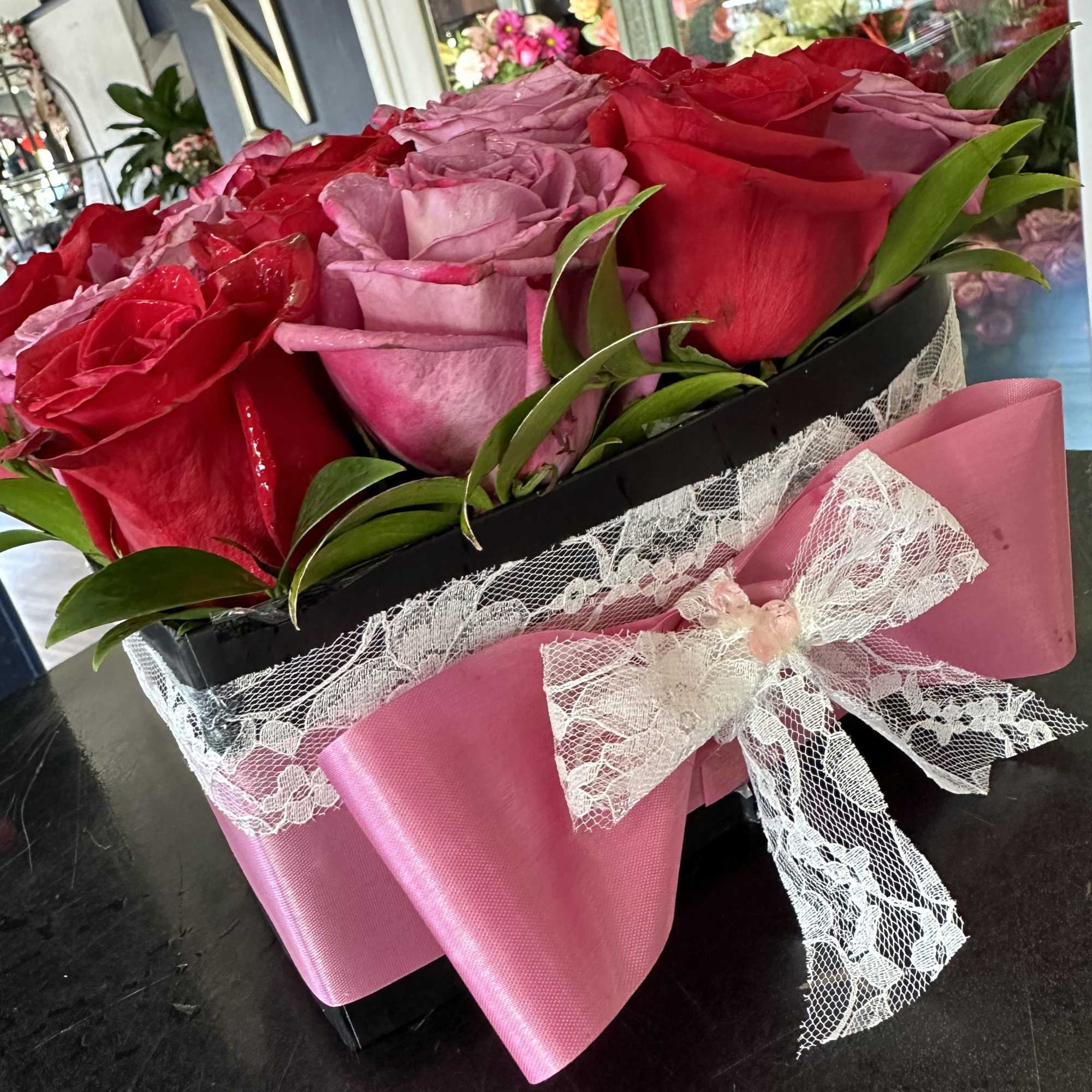 Boxed bouquet of red and pink roses with a pink ribbon