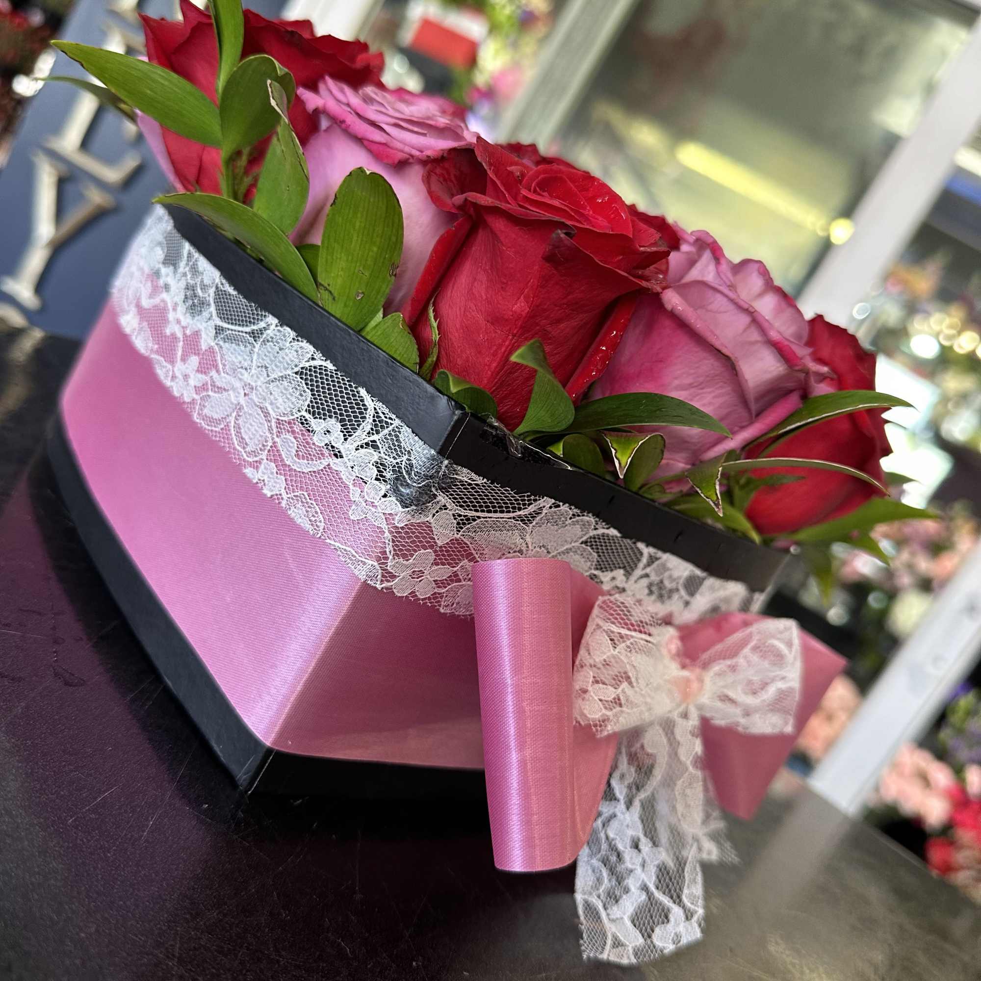 Pink and red roses in a black box with lace and ribbon