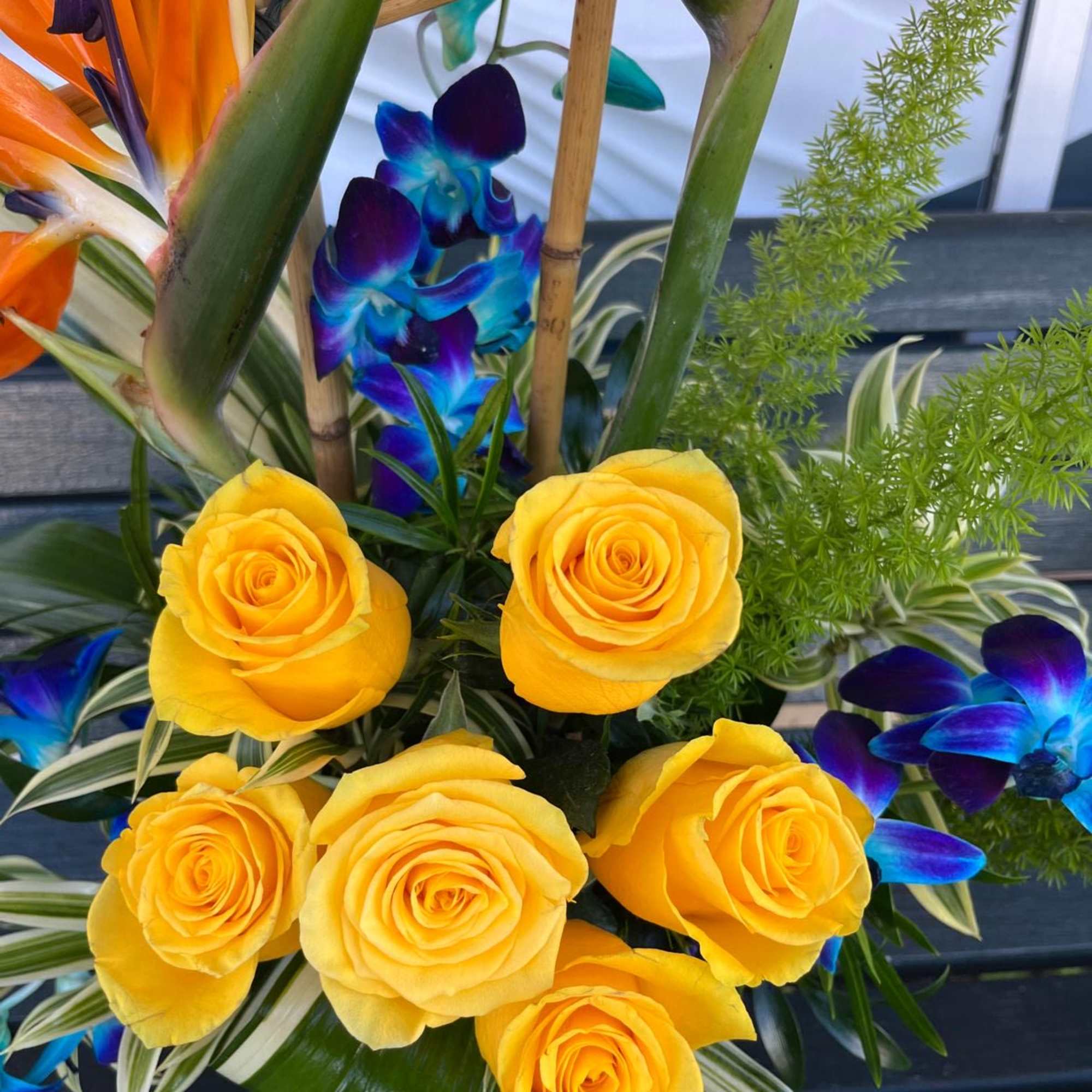 Yellow roses with blue orchids in a tropical arrangement