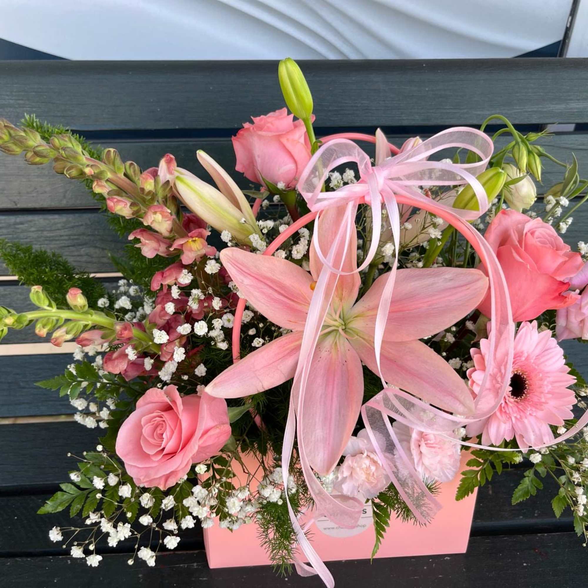 Pink floral arrangement with lilies, roses, and a gerbera daisy in a pink box