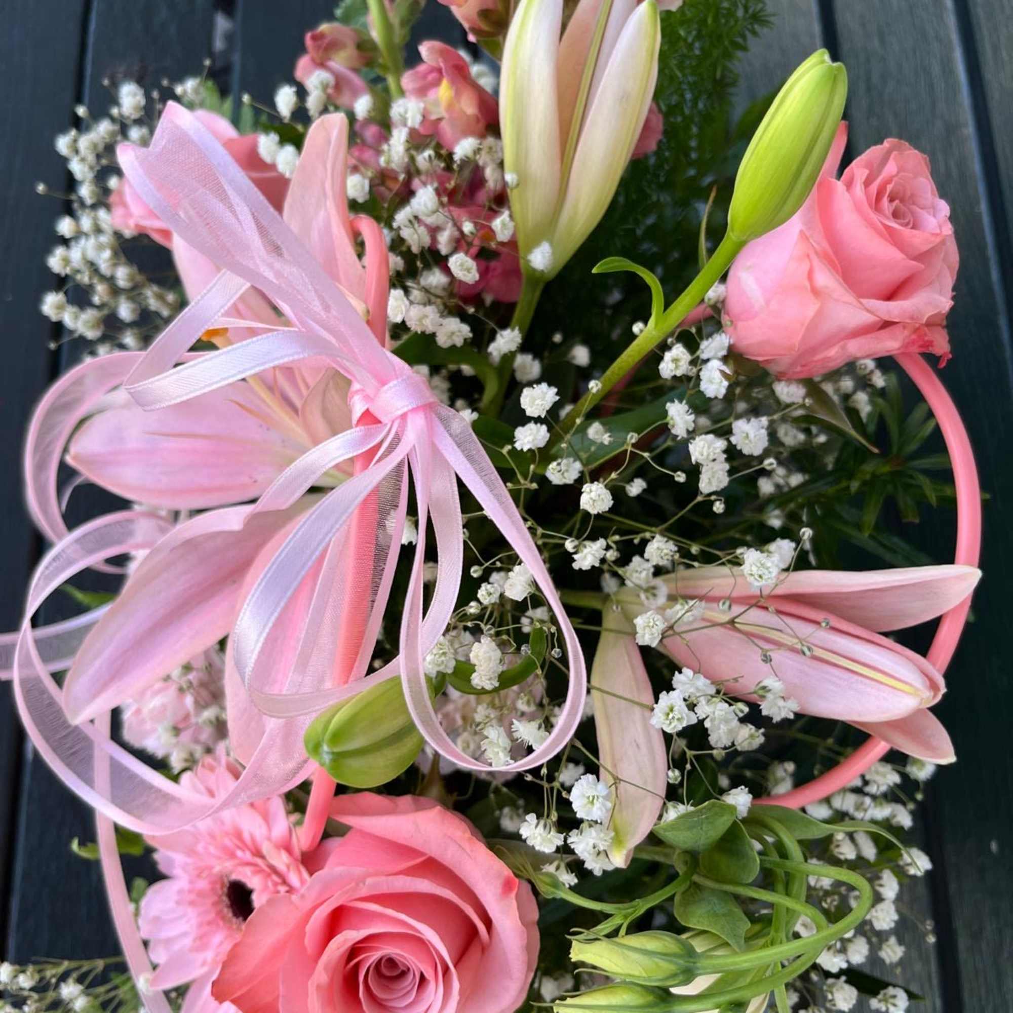 Pink roses and lilies with baby's breath and a ribbon bow