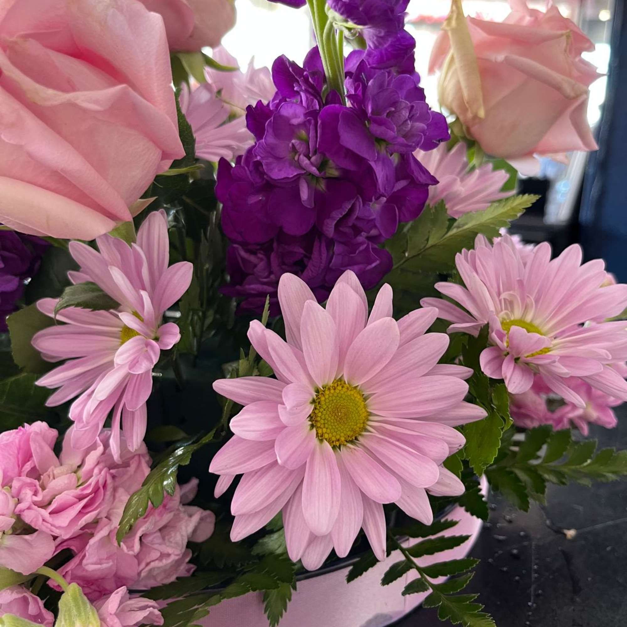 Pink roses and daisies with purple flowers in a box