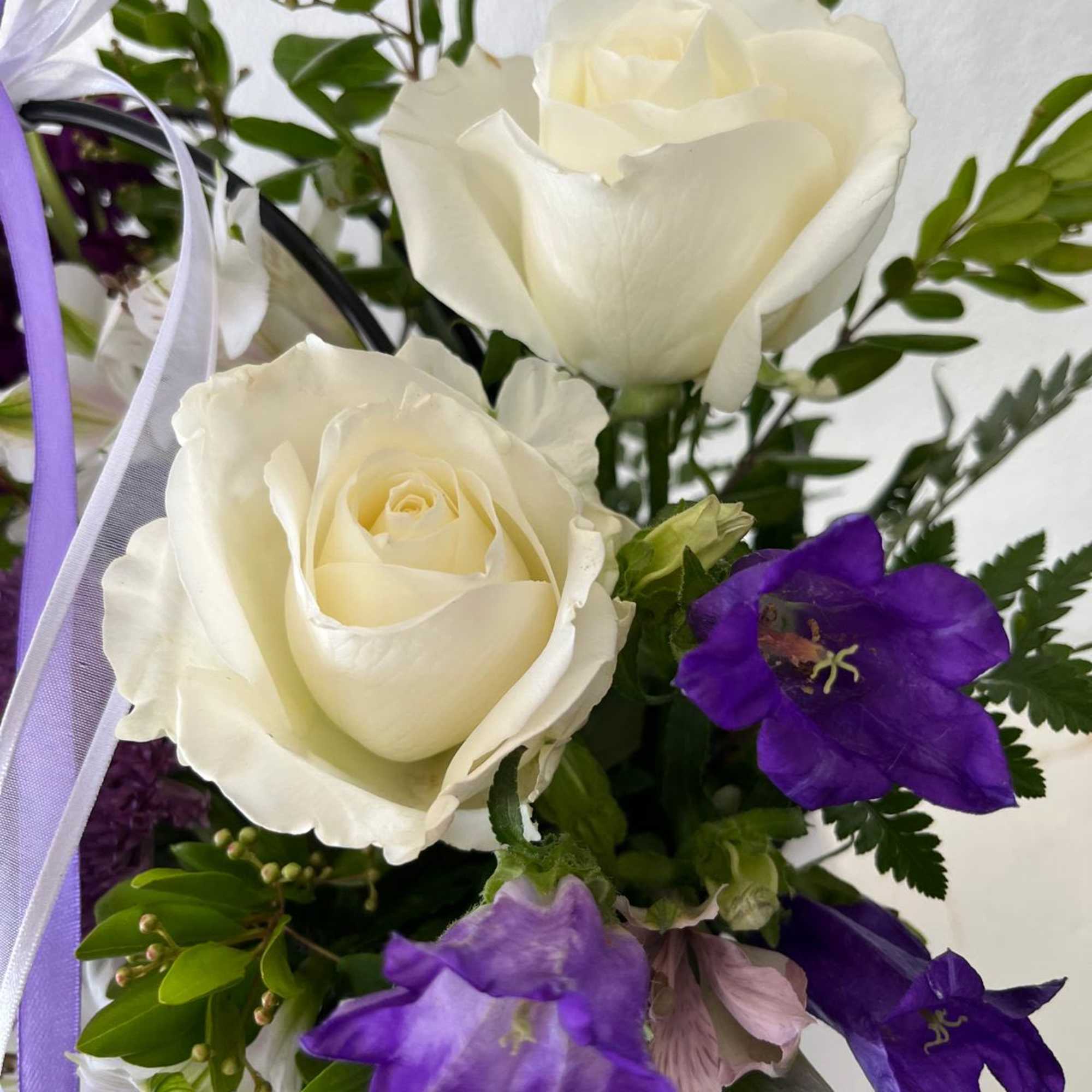 White roses with purple bellflowers and ribbon accents