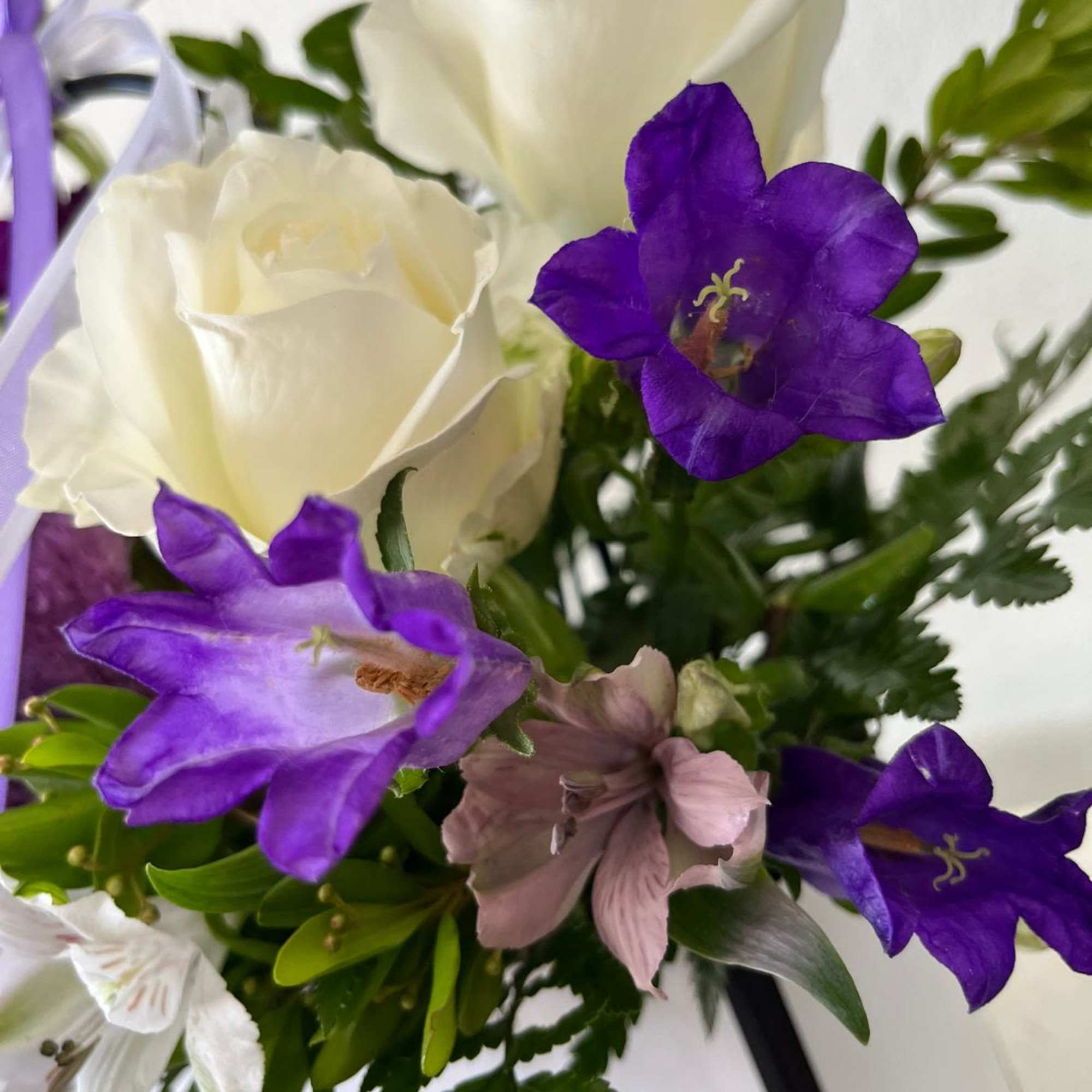 Bouquet of white roses and purple bellflowers with greenery