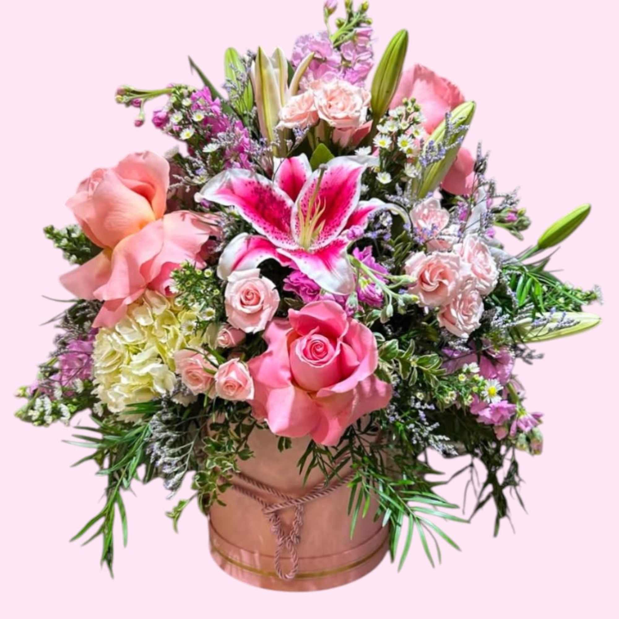 Pink and white floral arrangement in a round box with lilies and roses