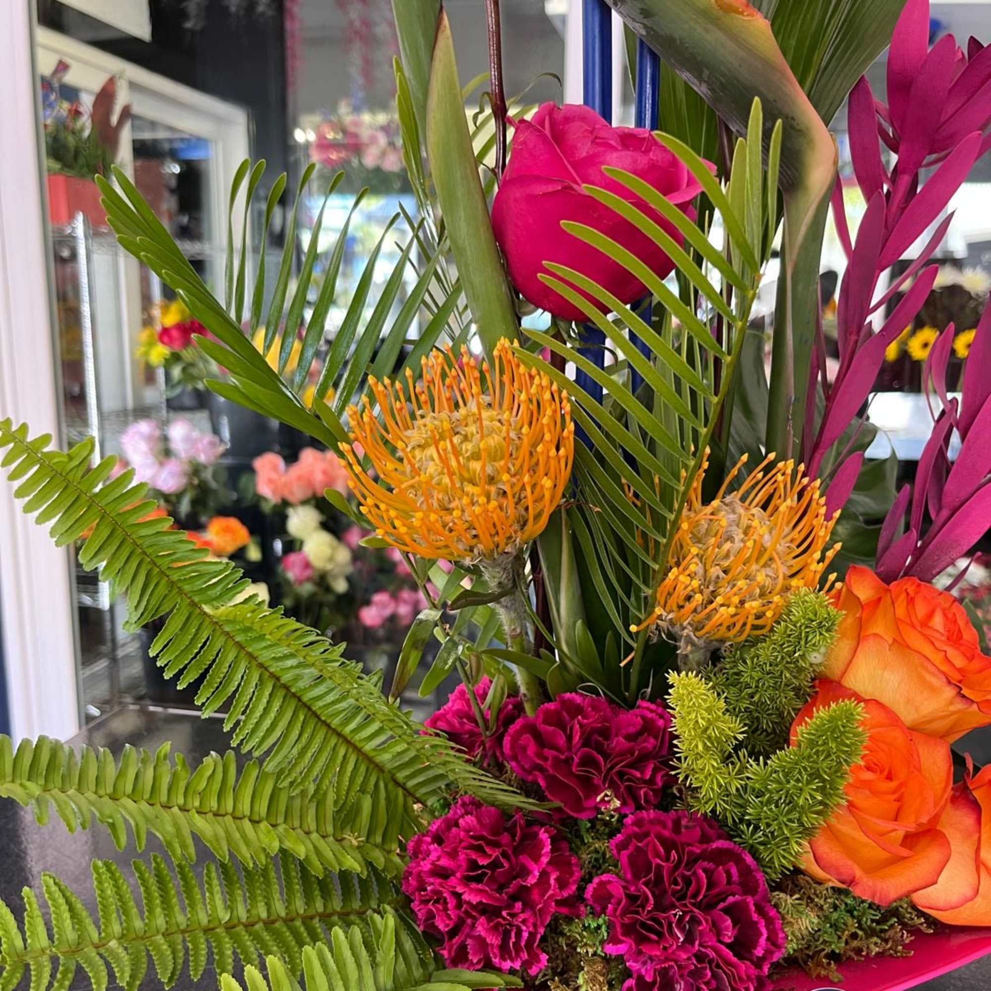 Tropical bouquet with orange roses, pink blooms, and bird of paradise