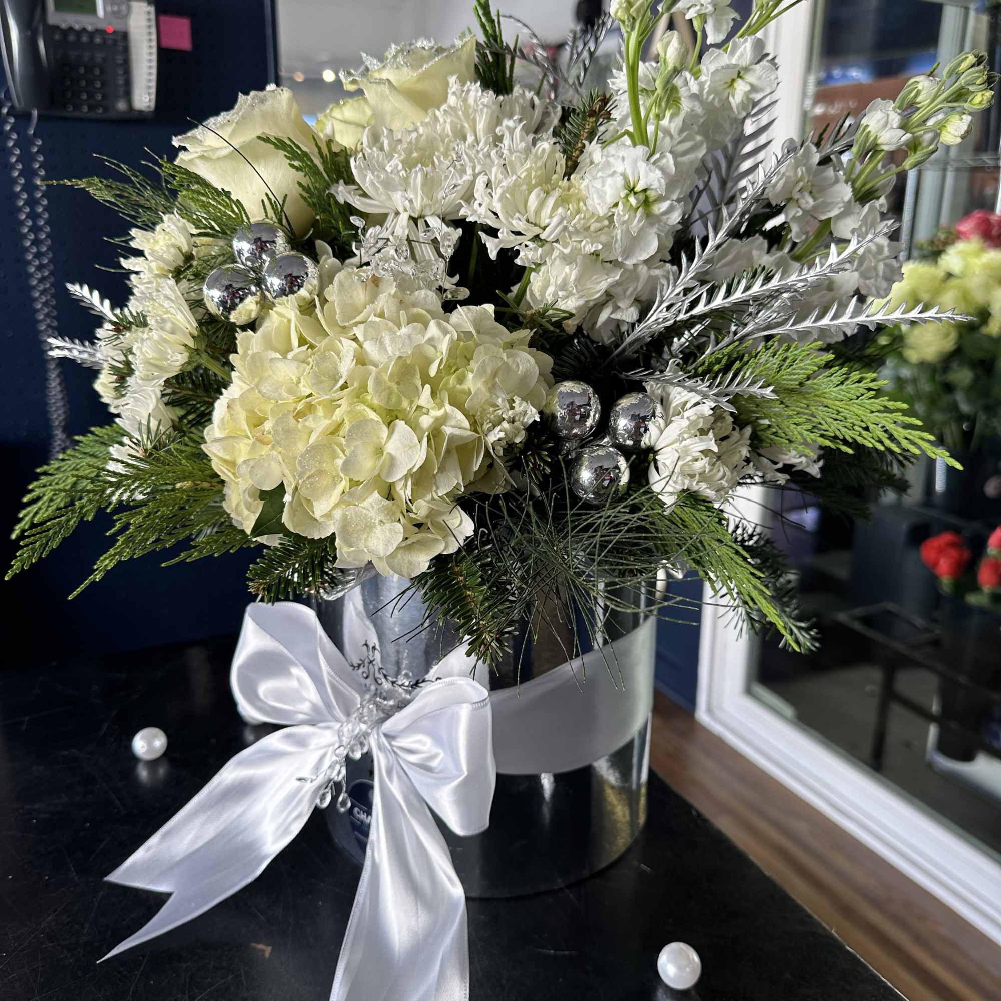 White floral arrangement in a silver box with a white ribbon