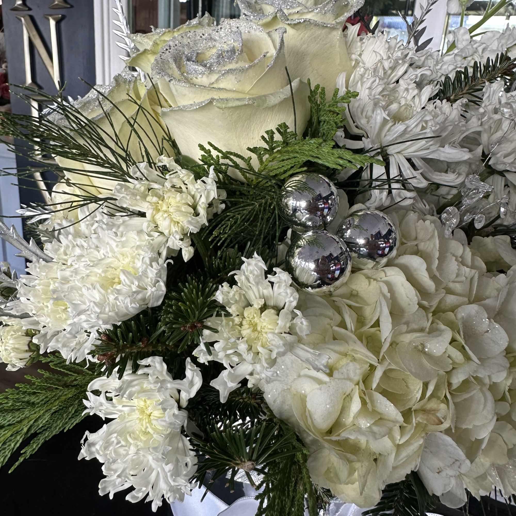 White floral arrangement with glittered roses and hydrangeas in a ribboned container
